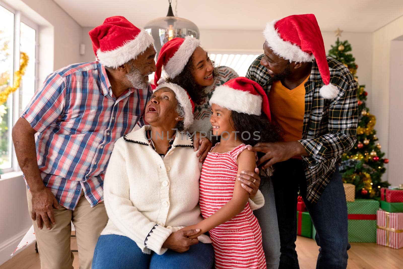 Happy multi generation family wearing santa hats, taking photo by Wavebreakmedia