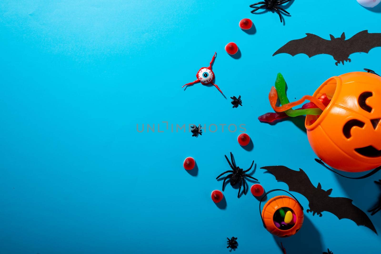 Close up view of multiple halloween candies and toys against blue background. halloween festivity and celebration concept