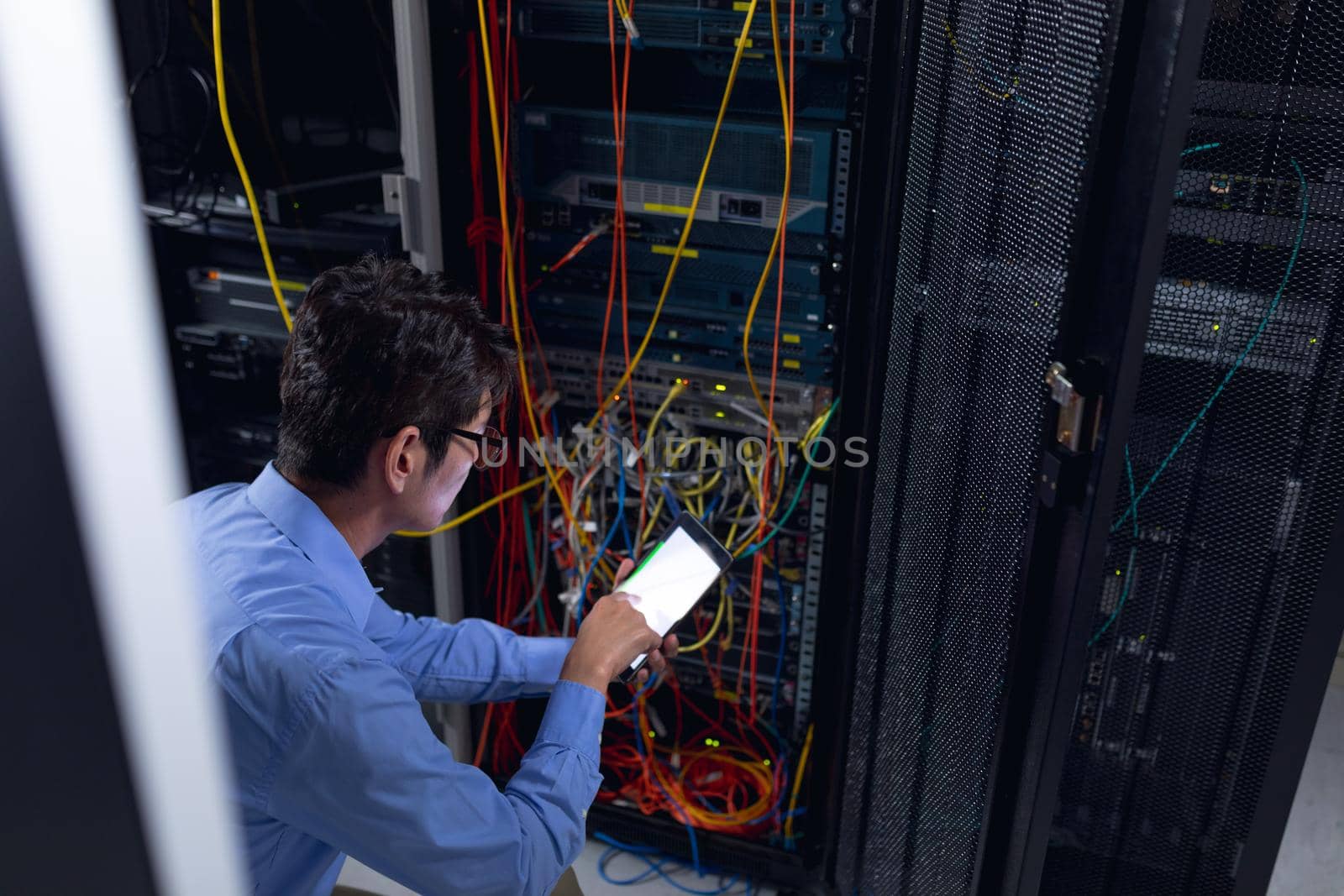Asian male engineer using digital tablet and inspecting computer server in computer server room by Wavebreakmedia