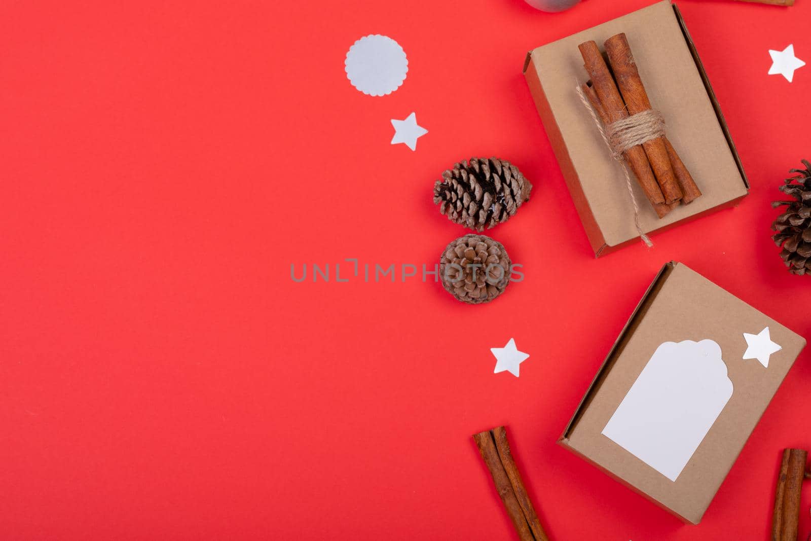 Composition of christmas decorations with pine cones, cinnamon and copy space on red background by Wavebreakmedia