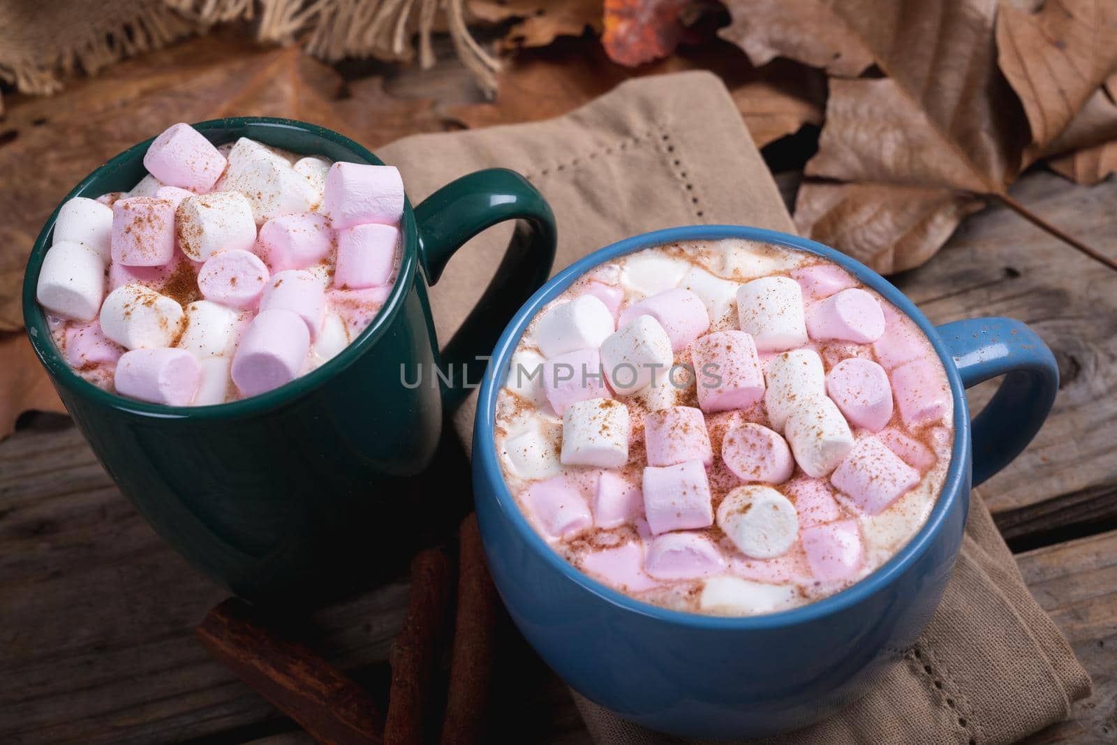 Pink and white marshmallows with hot chocolate drink filled in mugs on table at cafe by Wavebreakmedia