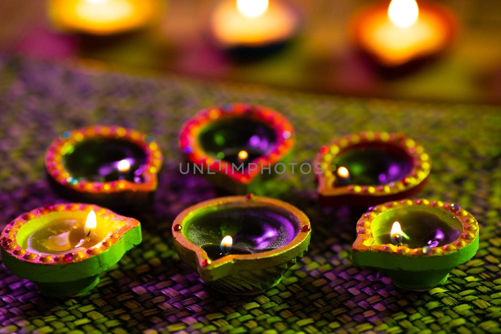 Lit candles in small decorative clay pots burning on woven table cloth. celebration, religion, tradition and ceremony concept.