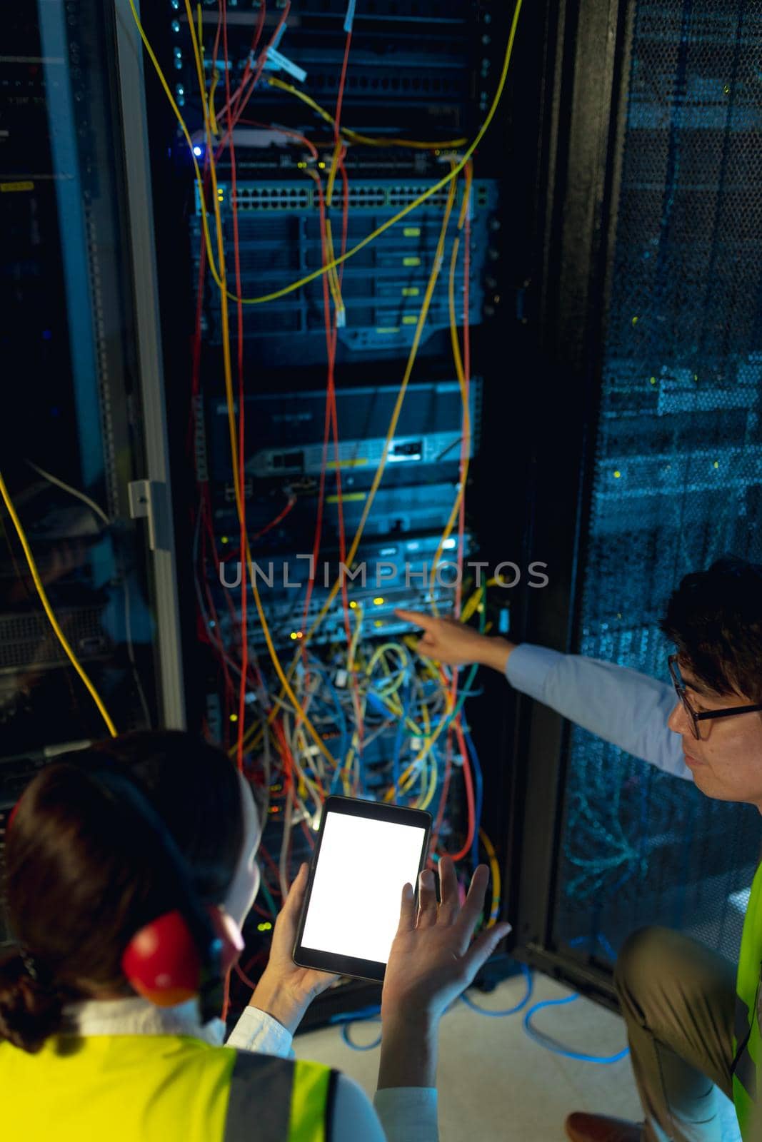 Diverse male and female engineer using digital tablet while inspecting in computer server room. database server management and maintenance concept