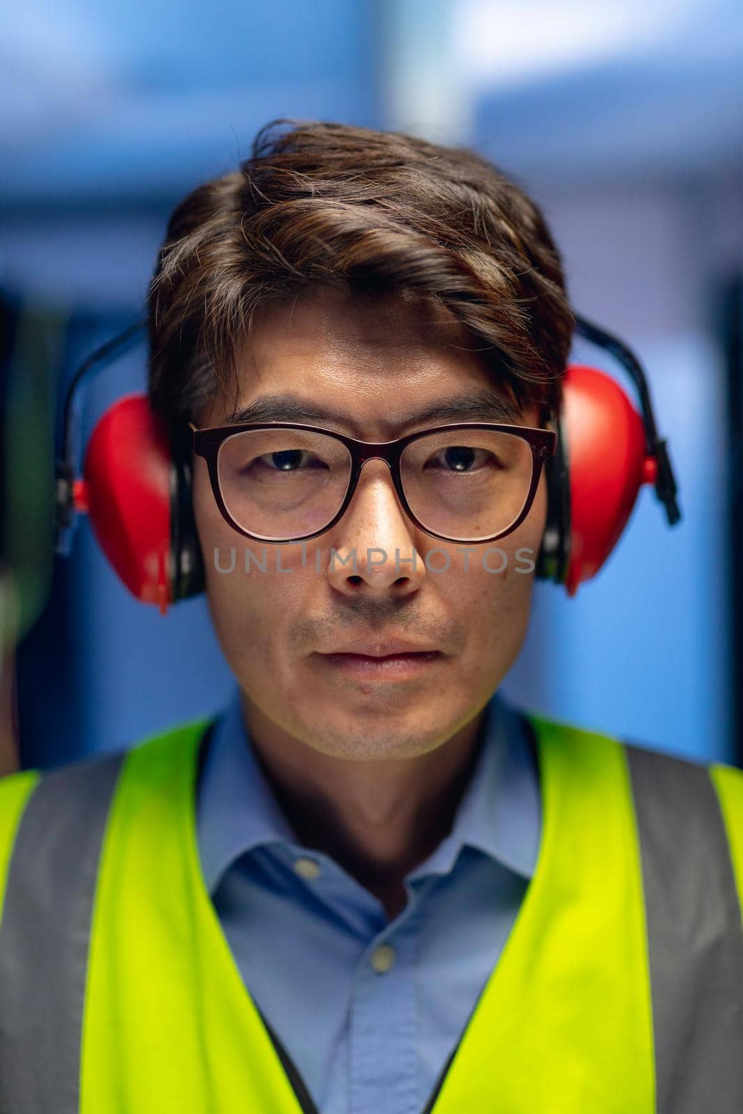 Portrait of asian male engineer wearing ear plugs in computer server room. database server management and maintenance concept