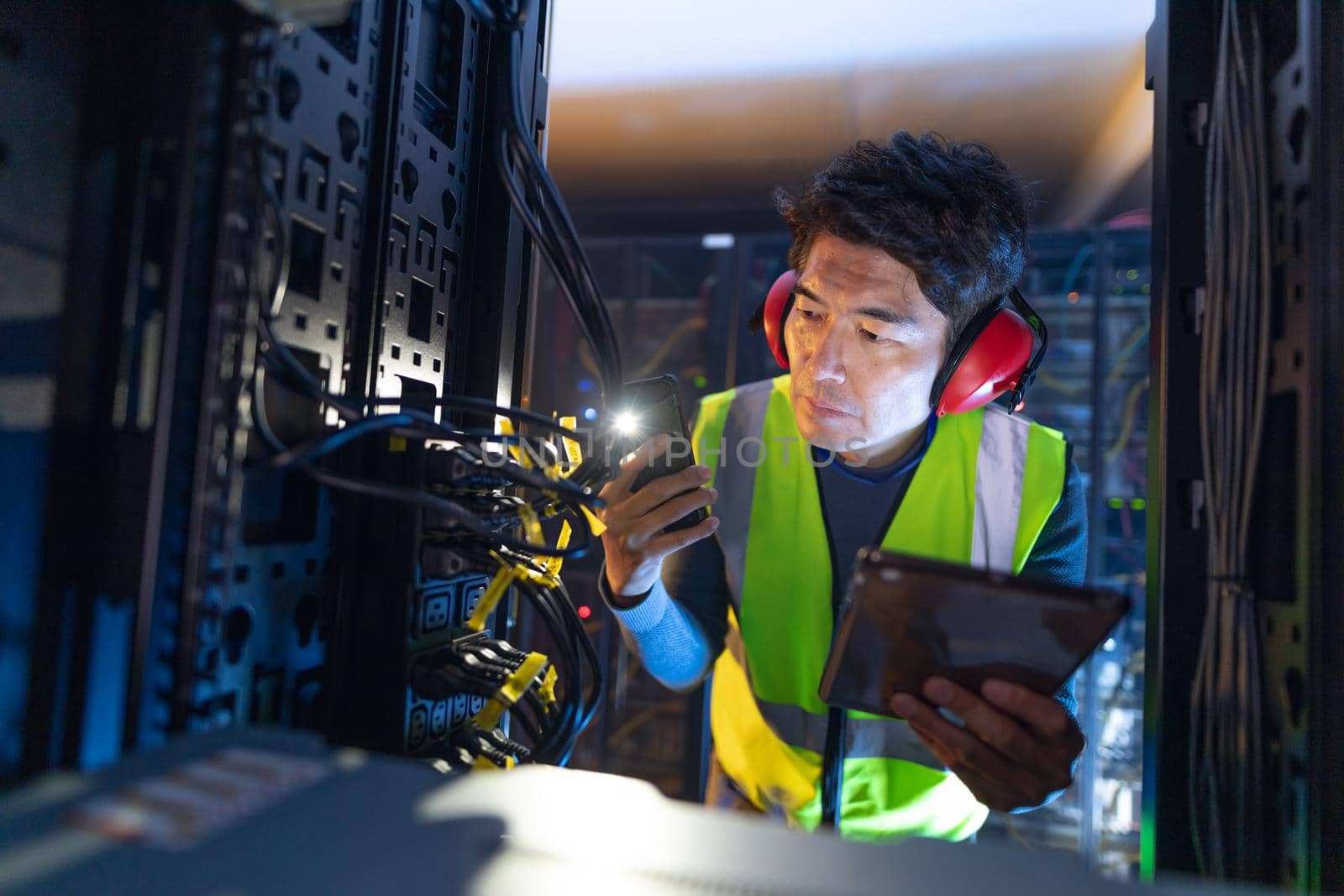 Asian male engineer using smartphone flash while inspecting the server in computer server room by Wavebreakmedia