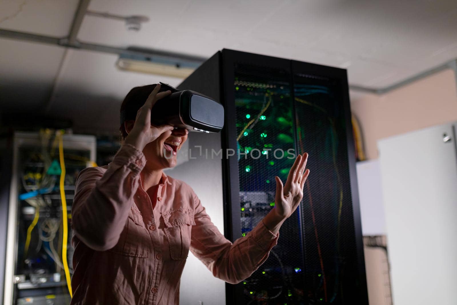 Caucasian woman smiling while wearing vr headset touching an invisible screen in server room by Wavebreakmedia