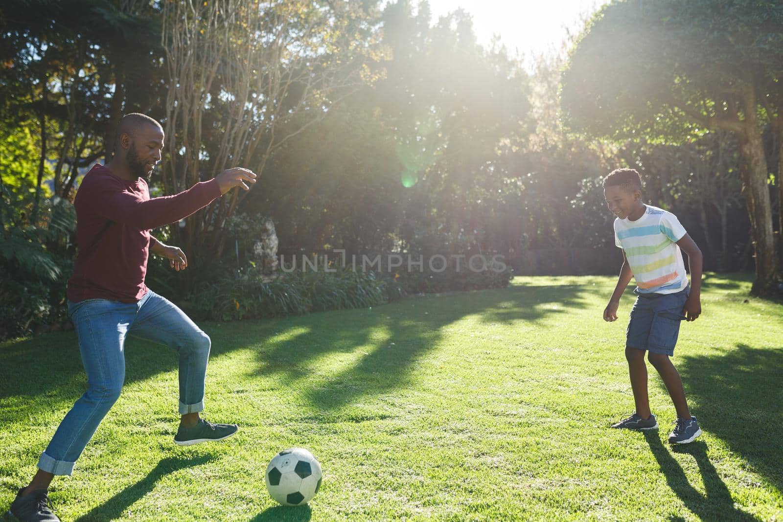 African american father with son having fun and playing football in garden by Wavebreakmedia