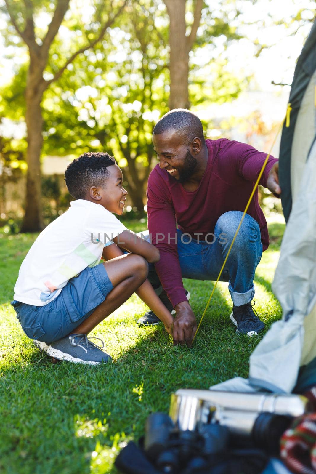 African american father with son having fun and pitching tent in garden by Wavebreakmedia