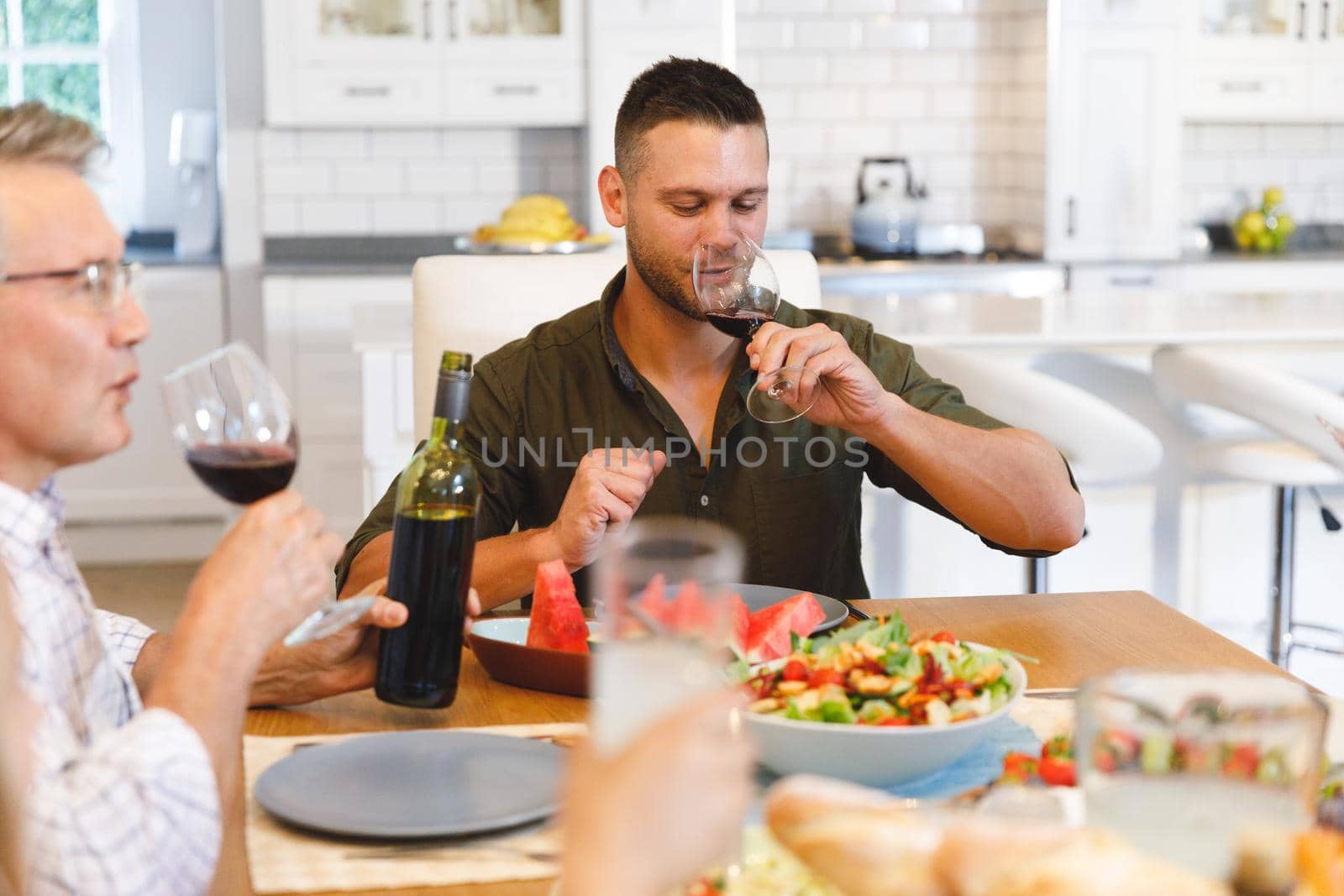 Caucasian grandfather with son sitting at table and having dinner by Wavebreakmedia