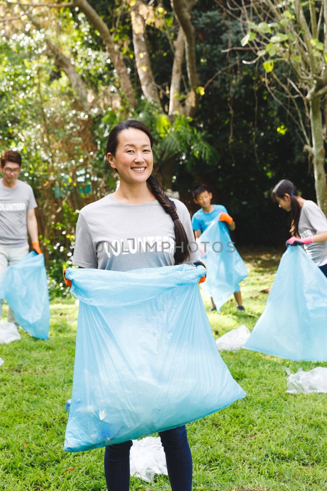 Portrait of smiling asian mother putting rubbish in refuse sacks with family in the countryside by Wavebreakmedia