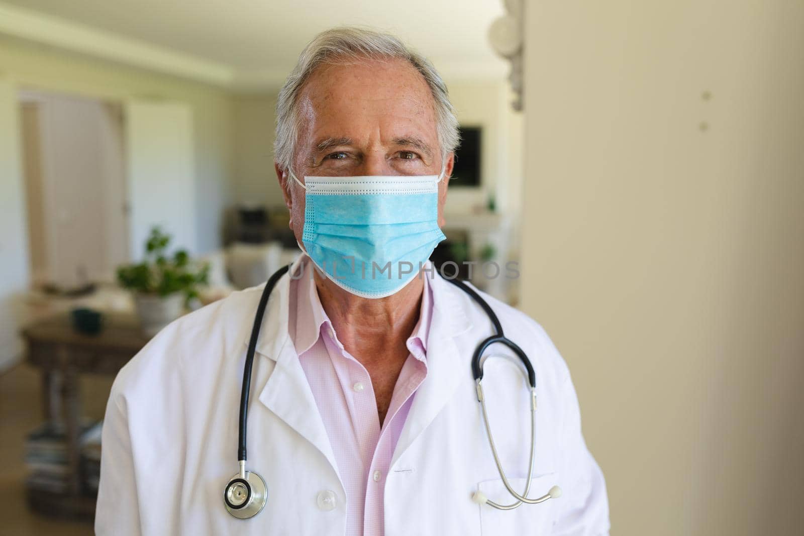 Portrait of senior caucasian male doctor wearing face mask looking at camera. medicine and healthcare services during covid 19 pandemic concept.