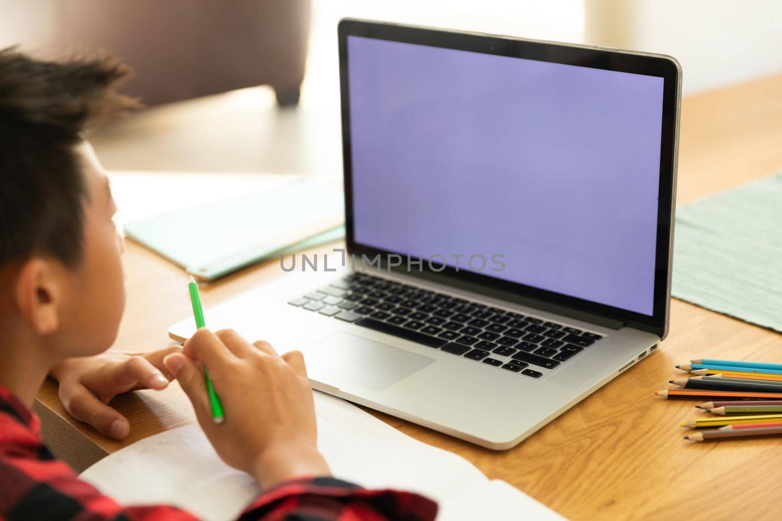 Asian boy using laptop with blank screen at home by Wavebreakmedia