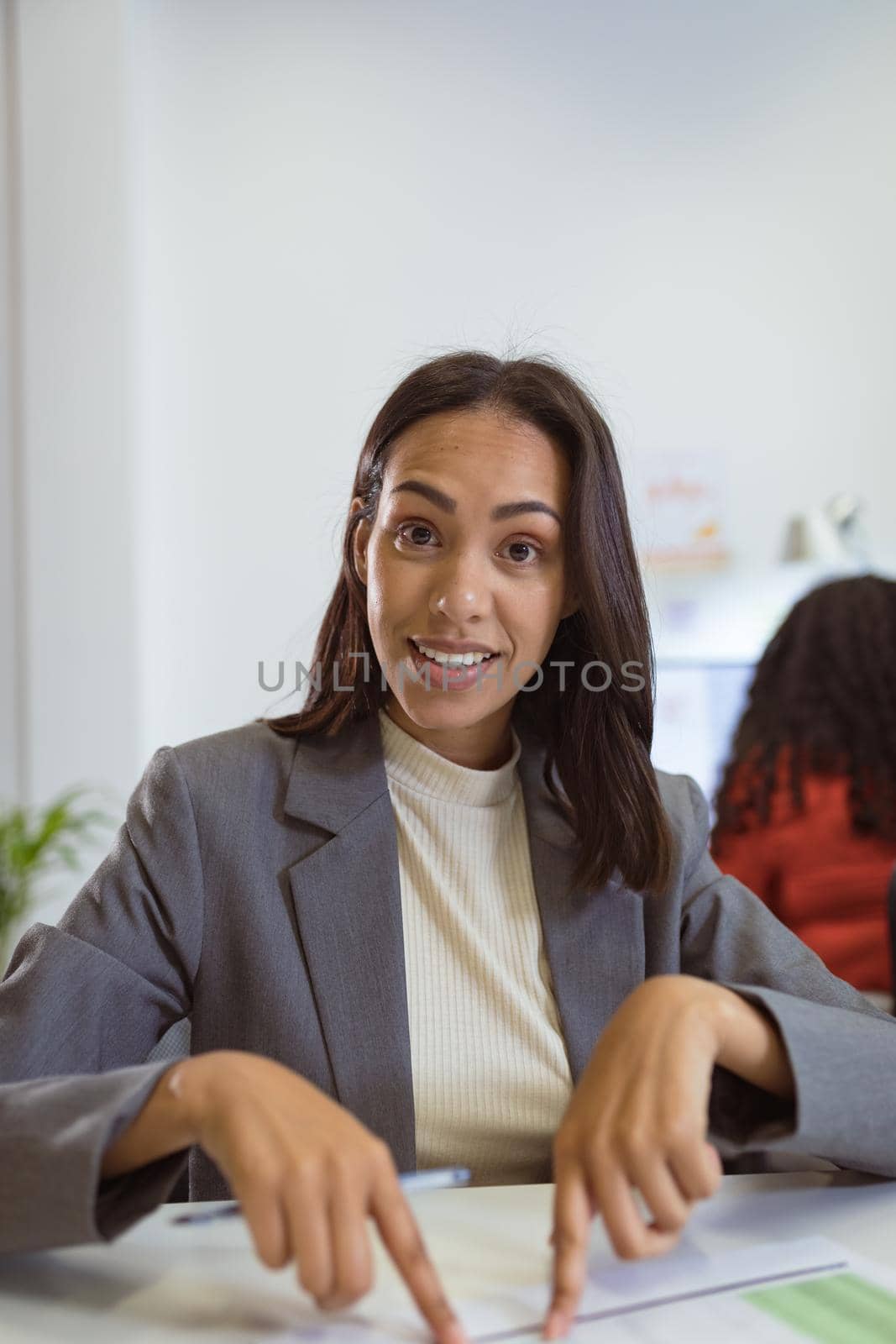 Smiling biracial businesswoman sitting at desk making video call in modern office. business and office workplace.