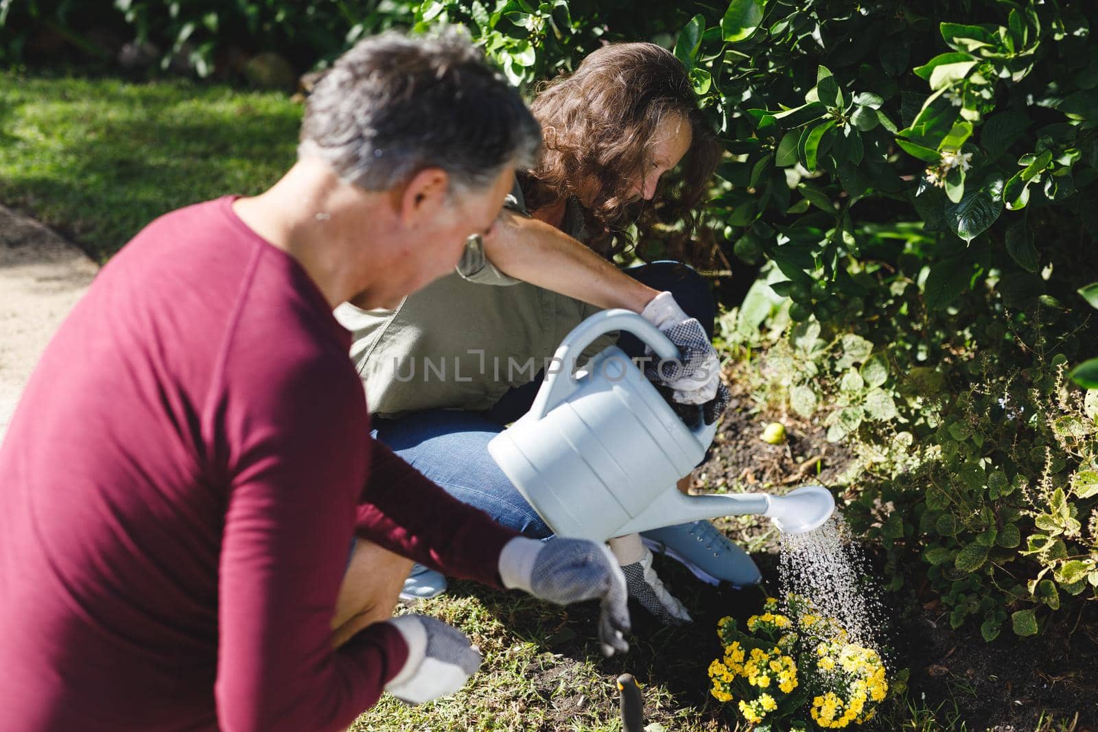 Happy senior caucasian couple gardening together in sunny garden by Wavebreakmedia