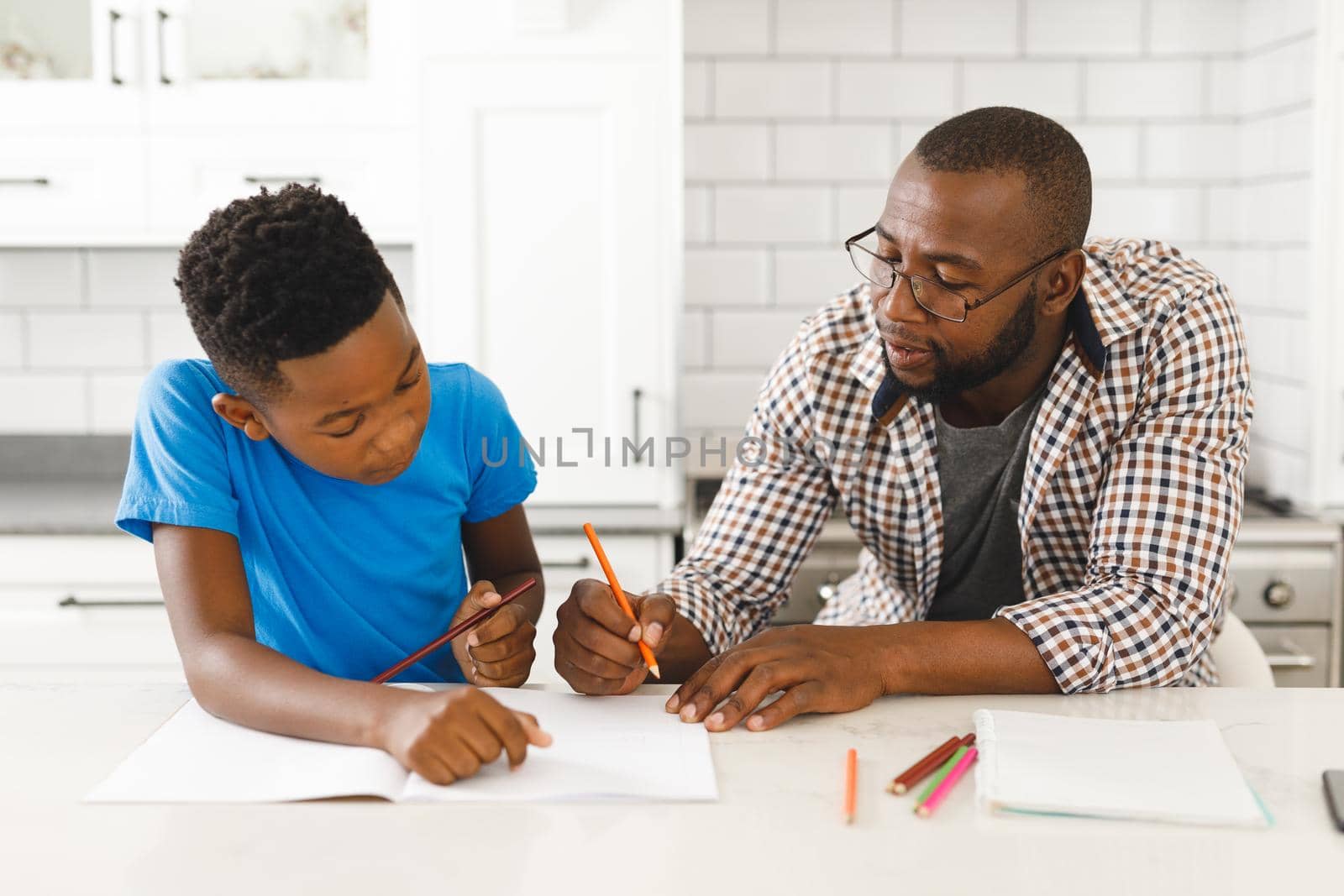 African american father and his son in kitchen, doing homework together by Wavebreakmedia