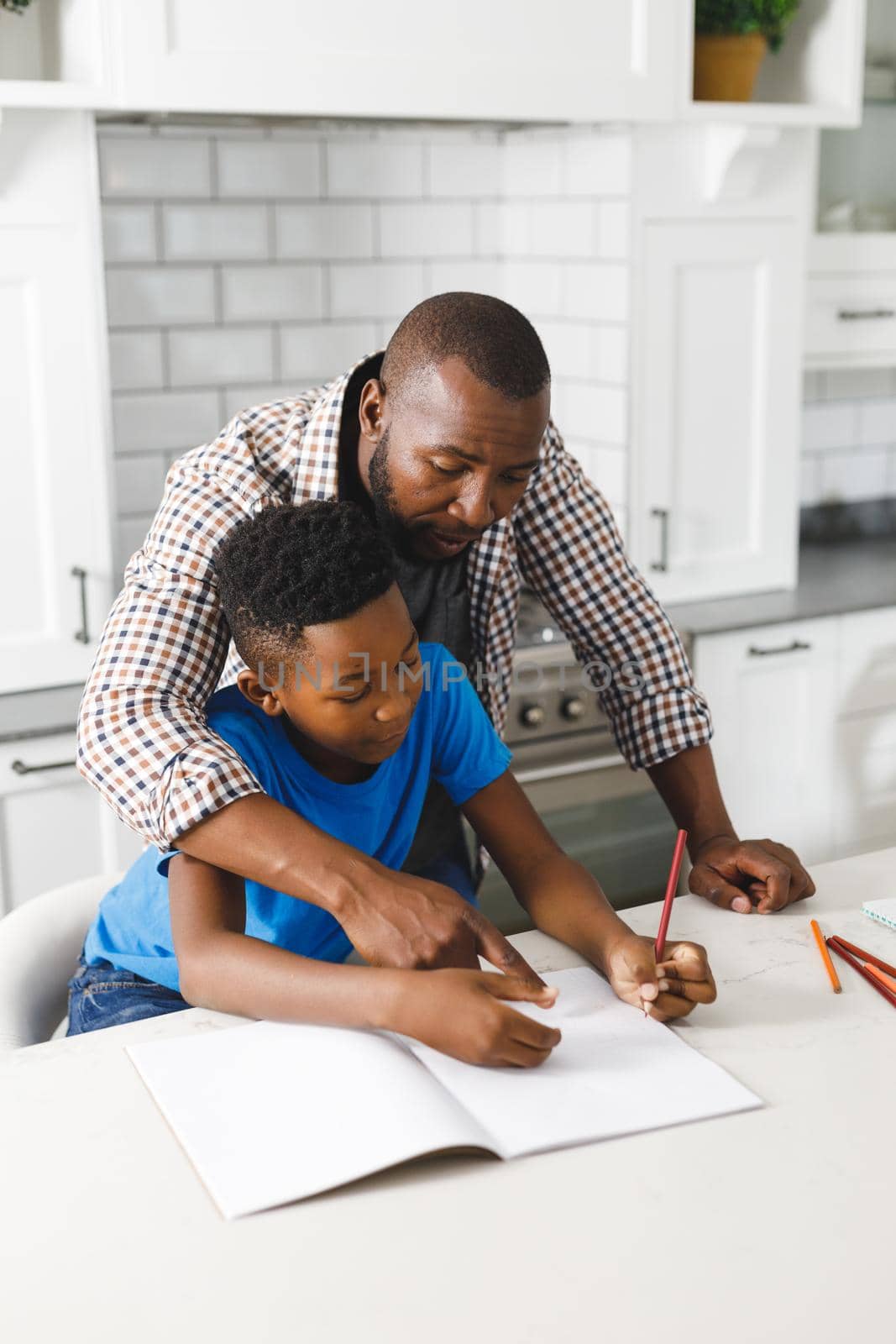 African american father and his son in kitchen, doing homework together by Wavebreakmedia