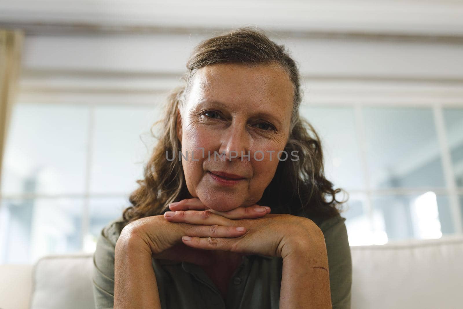 Smiling senior caucasian woman in living room, sitting on sofa, making video call by Wavebreakmedia