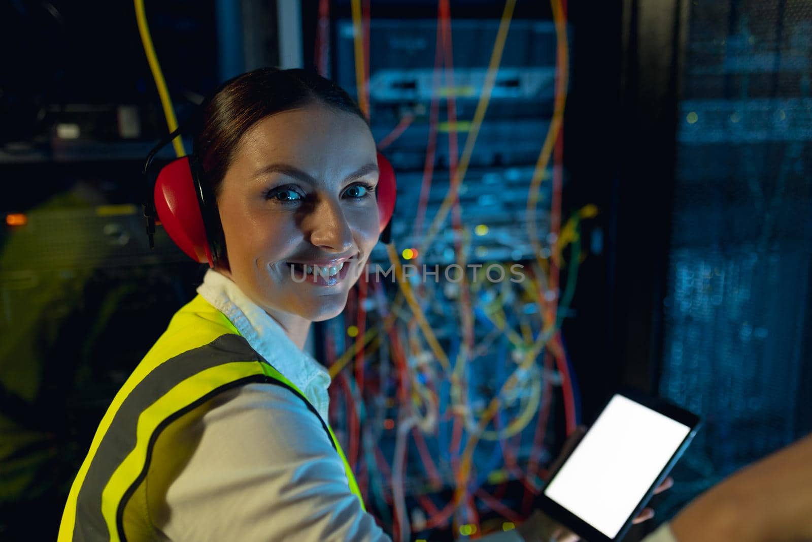 Portrait of caucasian female engineer smiling while using digital tablet in computer server room. database server management and maintenance concept