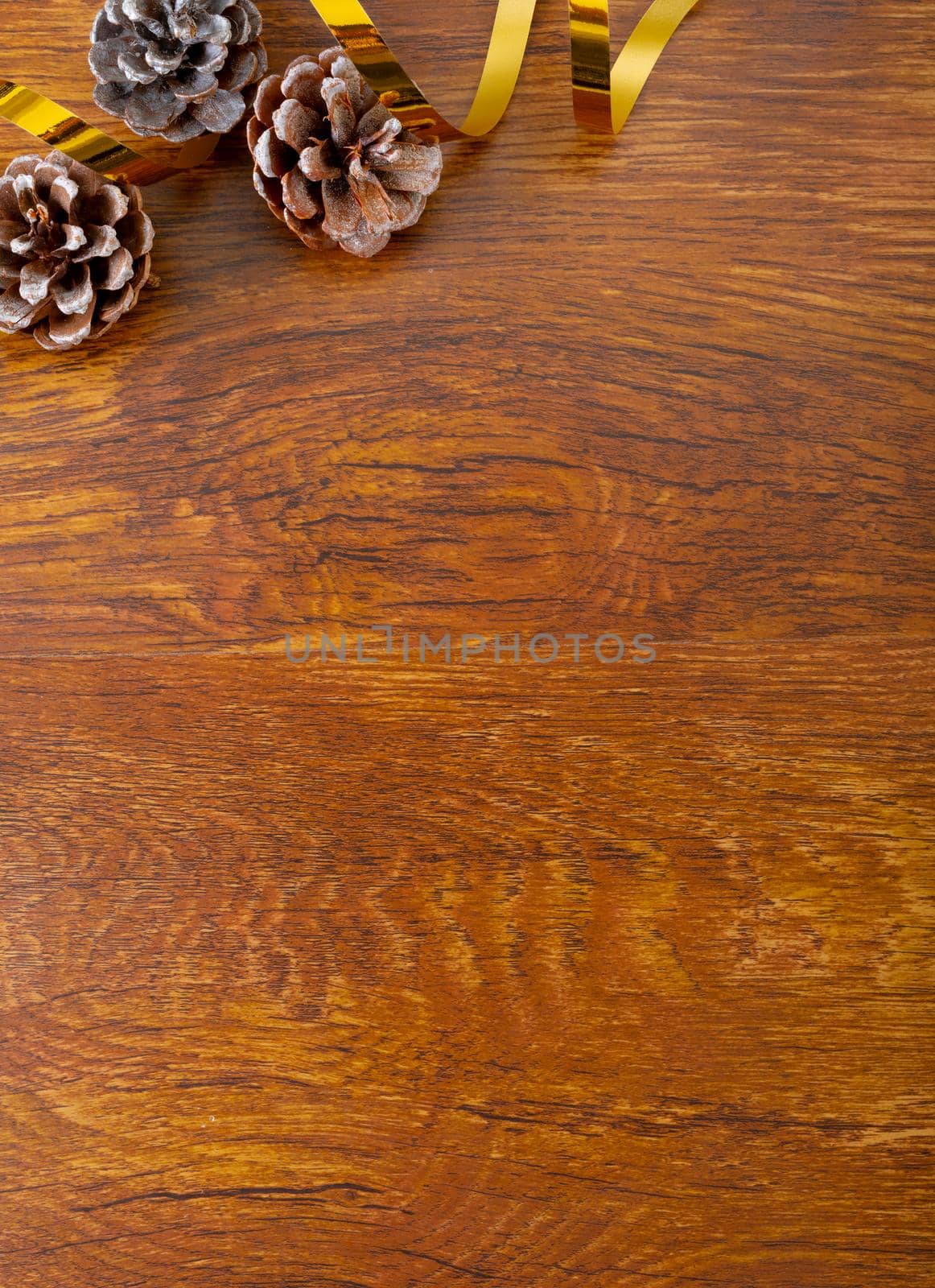 Composition of christmas decorations with pine cones and copy space on wooden background by Wavebreakmedia