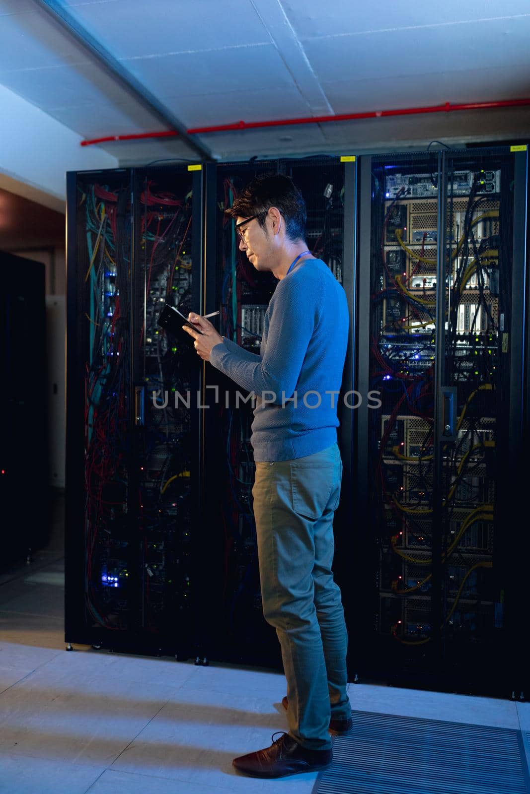 Asian male engineer writing on clipboard in computer server room by Wavebreakmedia