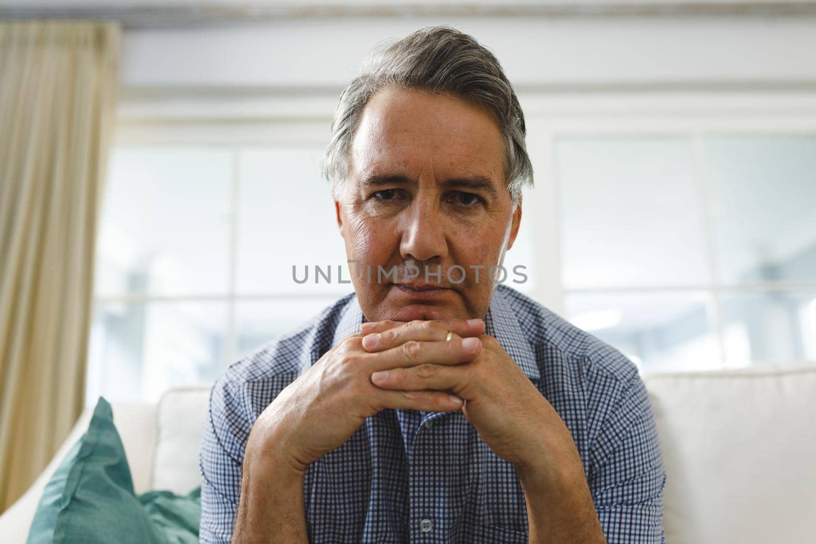 Senior caucasian man in living room, sitting on sofa listening during video call. retirement lifestyle, spending time at home with technology.