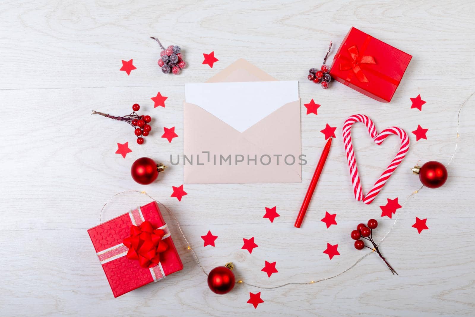Composition of christmas decorations with envelope, baubles, candy canes, stars on wooden background. christmas, tradition and celebration concept.