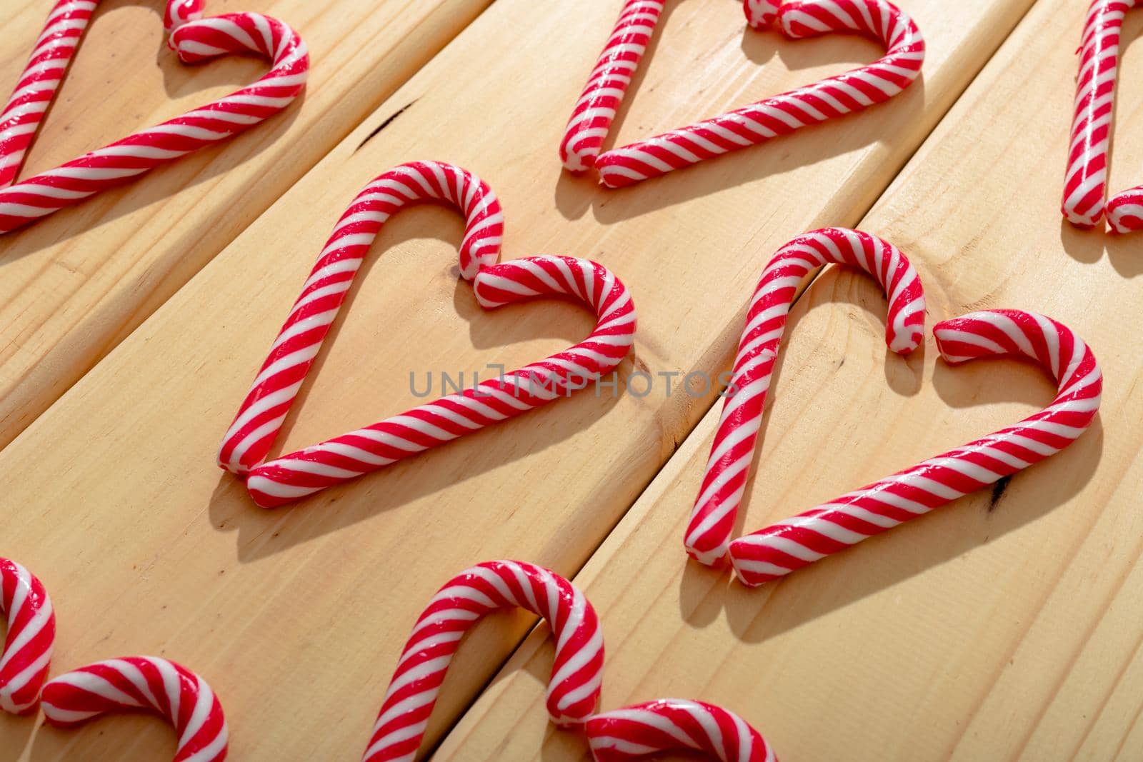 Composition of multiple candy canes in shape of heart on wooden background. christmas, tradition and celebration concept.