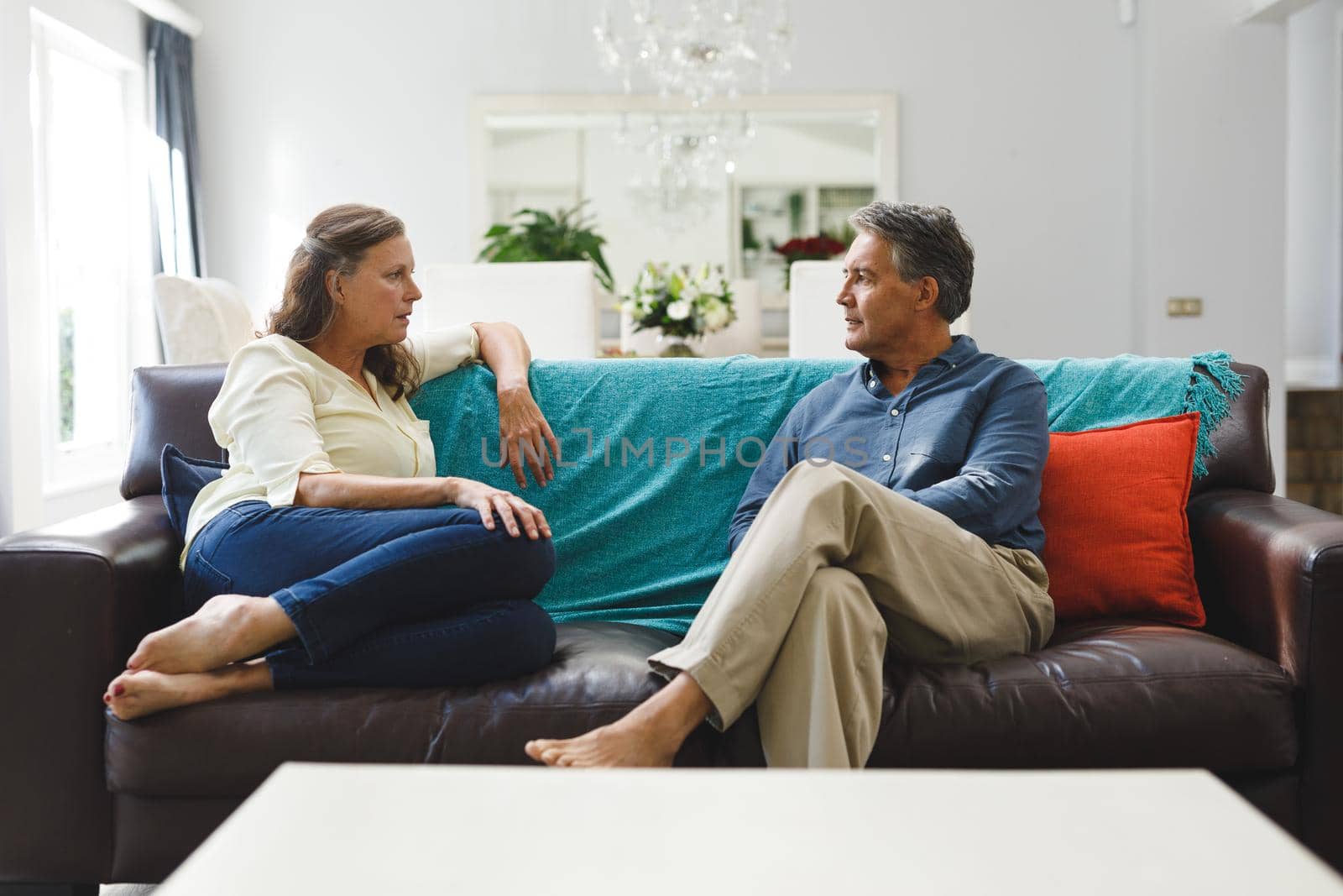 Happy senior caucasian couple in living room sitting on sofa, talking. retirement lifestyle, spending time at home.