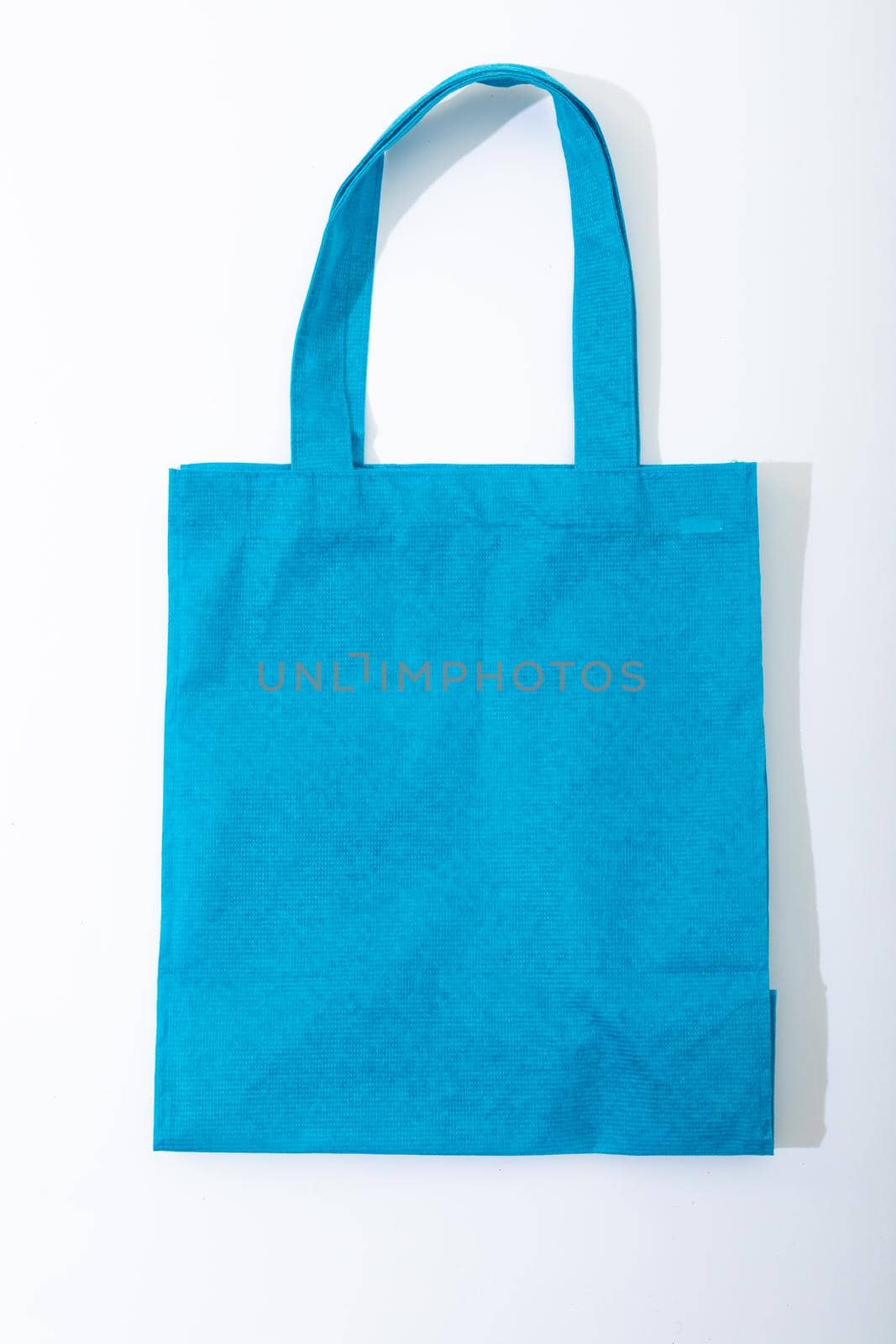 Composition of empty blue canvas shopping bag lying flat on white background. shopping and retail concept.