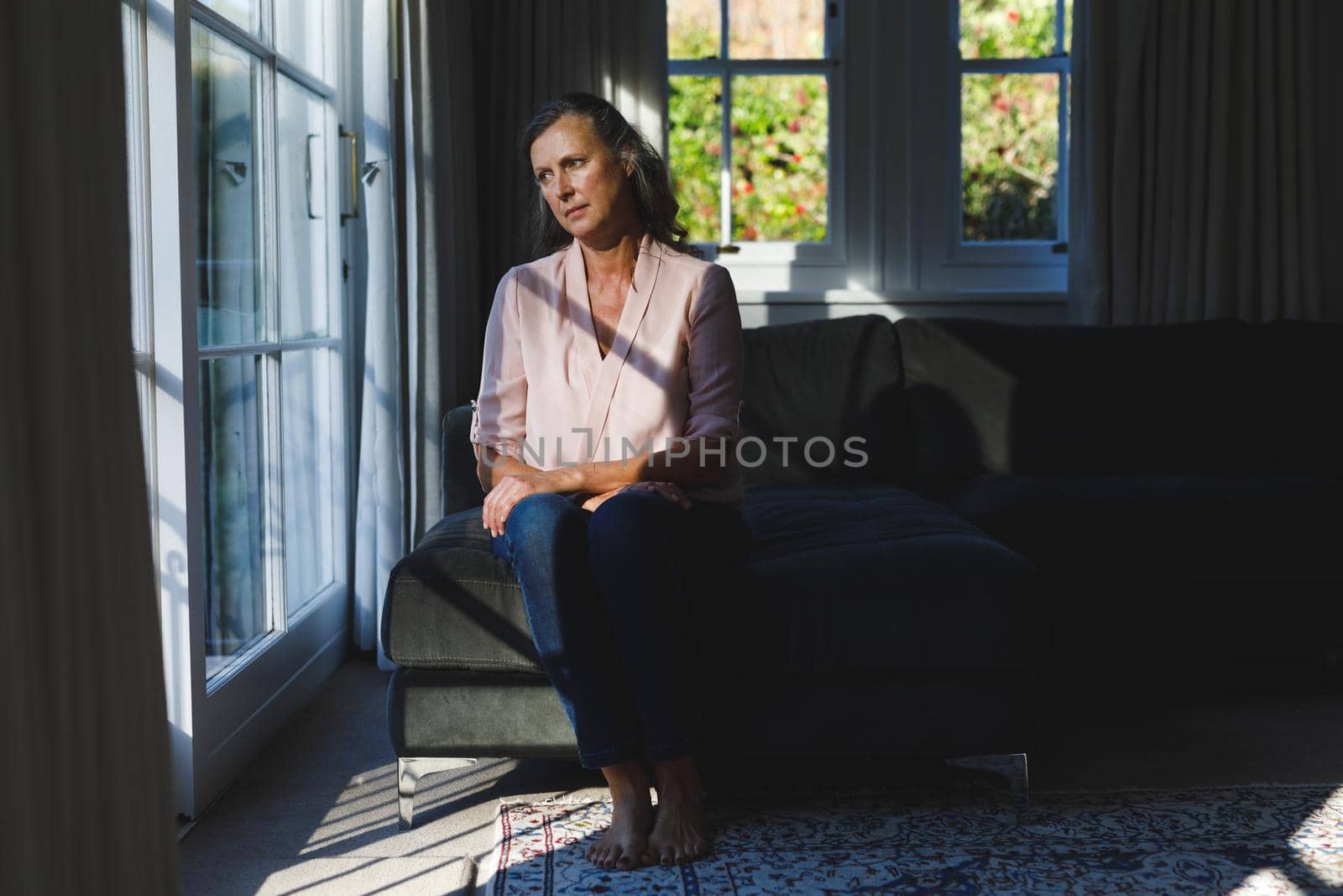 Thoughtful senior caucasian woman in bedroom, looking through window by Wavebreakmedia