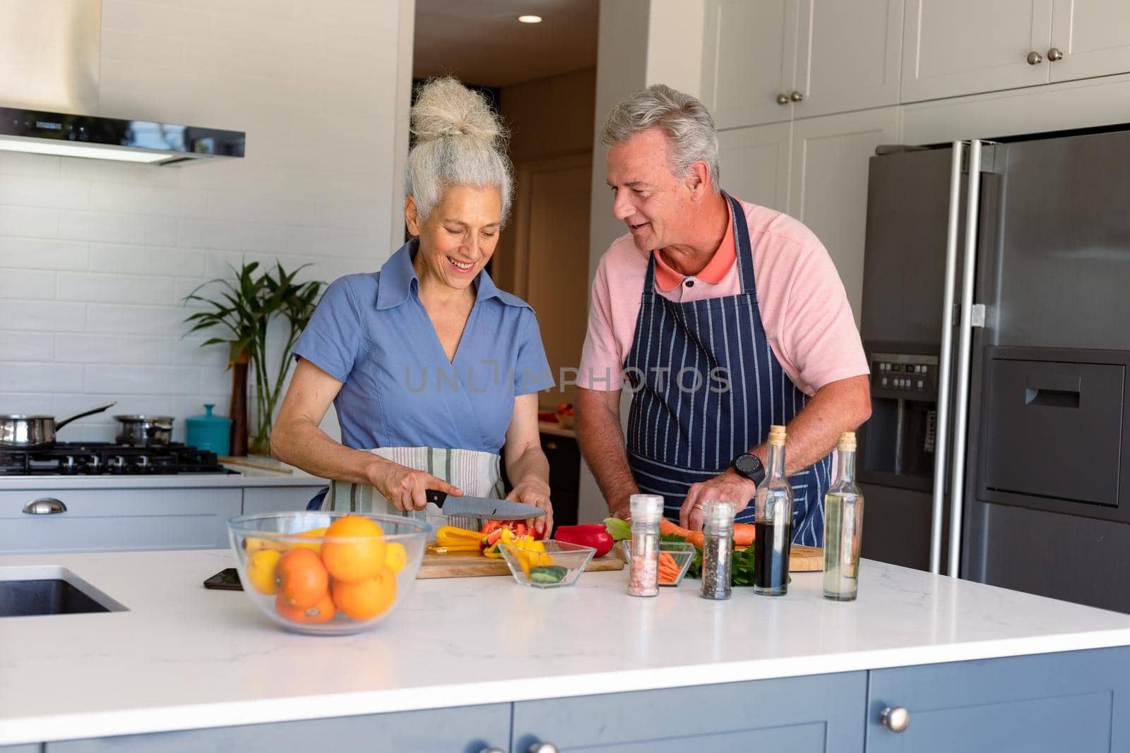 Happy caucasian senior couple standing in kitchen and preparing meal together by Wavebreakmedia