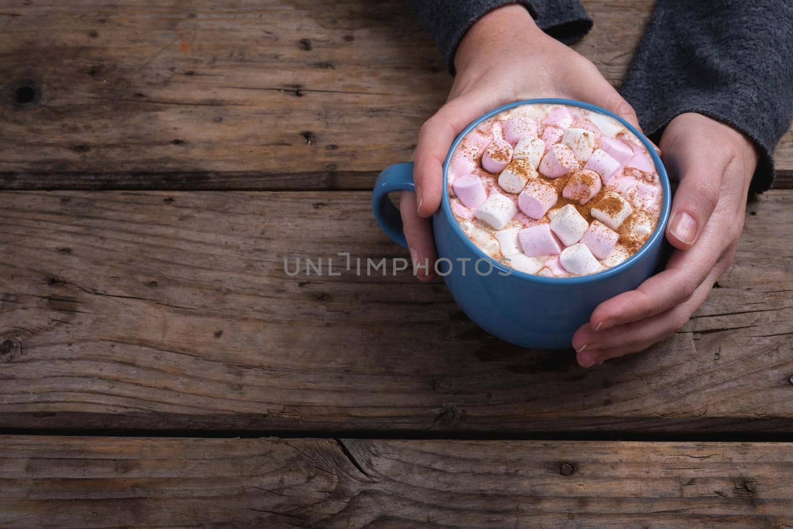 Cropped hands of woman holding mug of hot chocolate drink with copy space at table in coffee shop by Wavebreakmedia