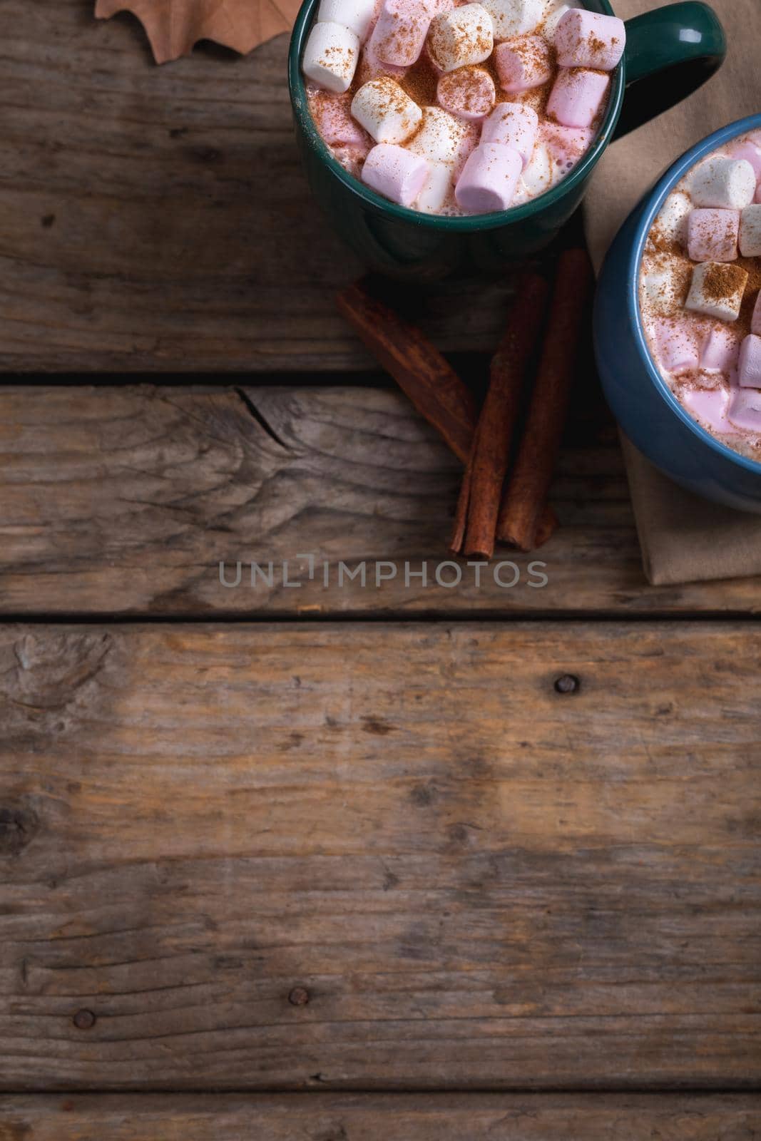 Cinnamon powder sprinkled on white and pink marshmallows in mugs on table with copy space by Wavebreakmedia