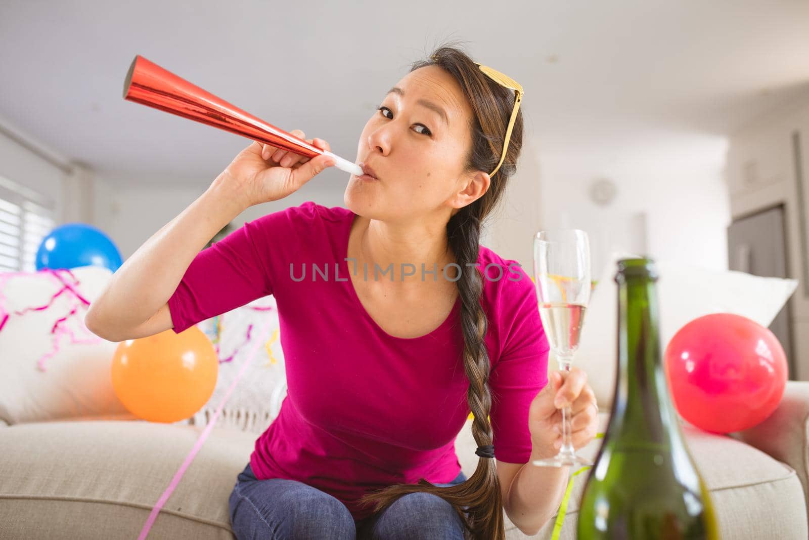 Happy asian woman raising party trumpet and champagne glass making new year's eve laptop video call by Wavebreakmedia