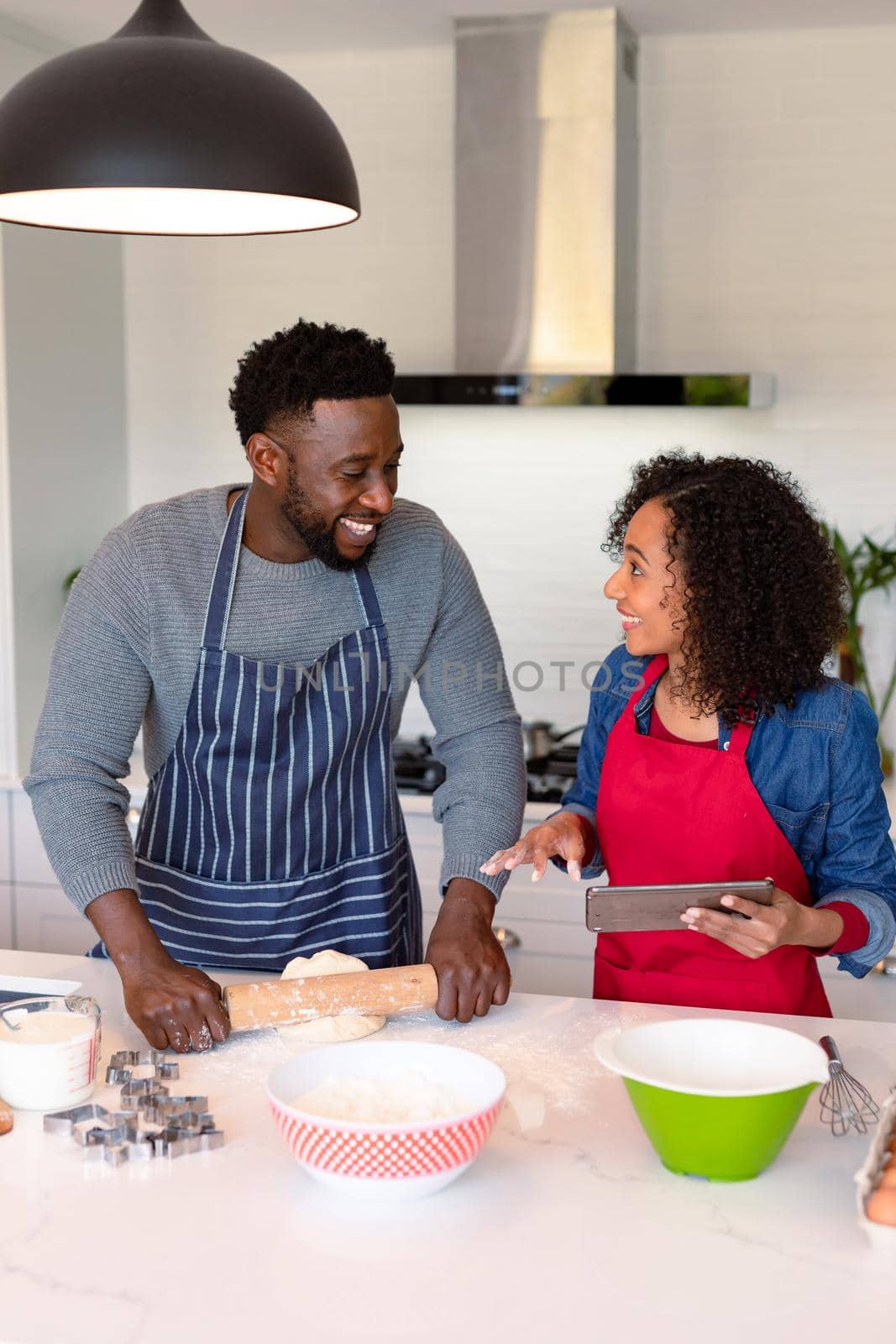 Happy african american couple wearing aprons, baking together and looking at camera by Wavebreakmedia