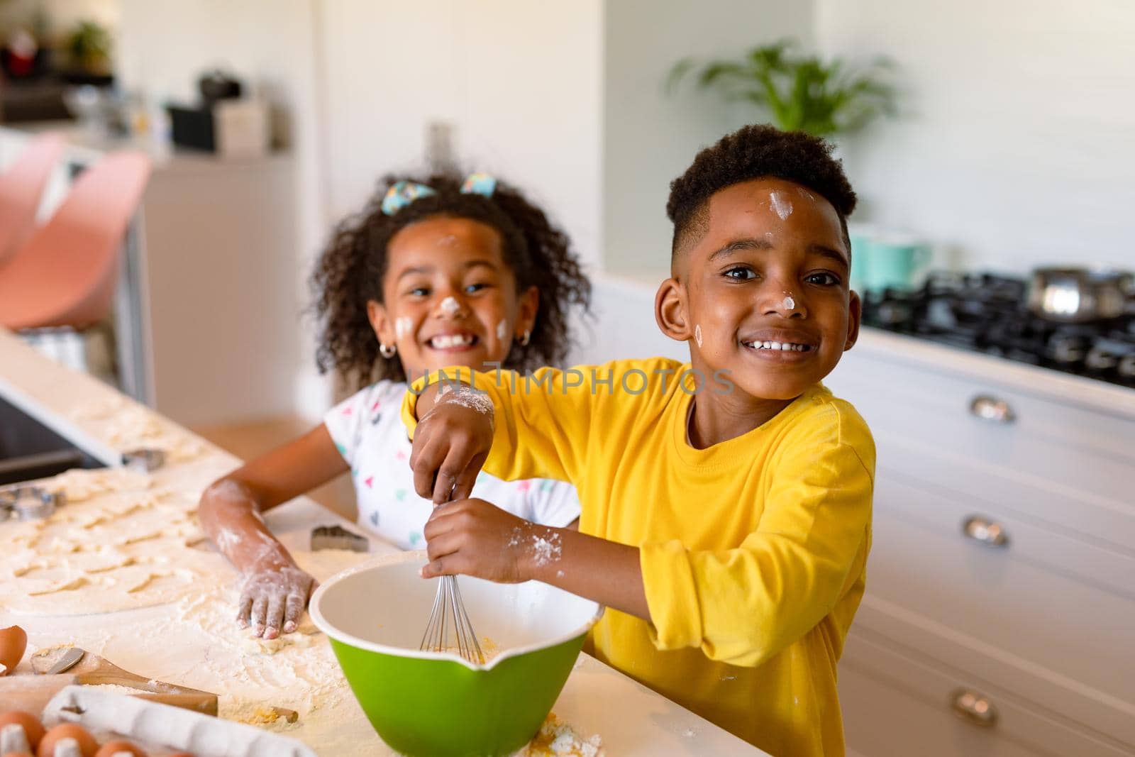 Happy african american siblings baking in kitchen. baking and cooking, childhood and leisure time at home.