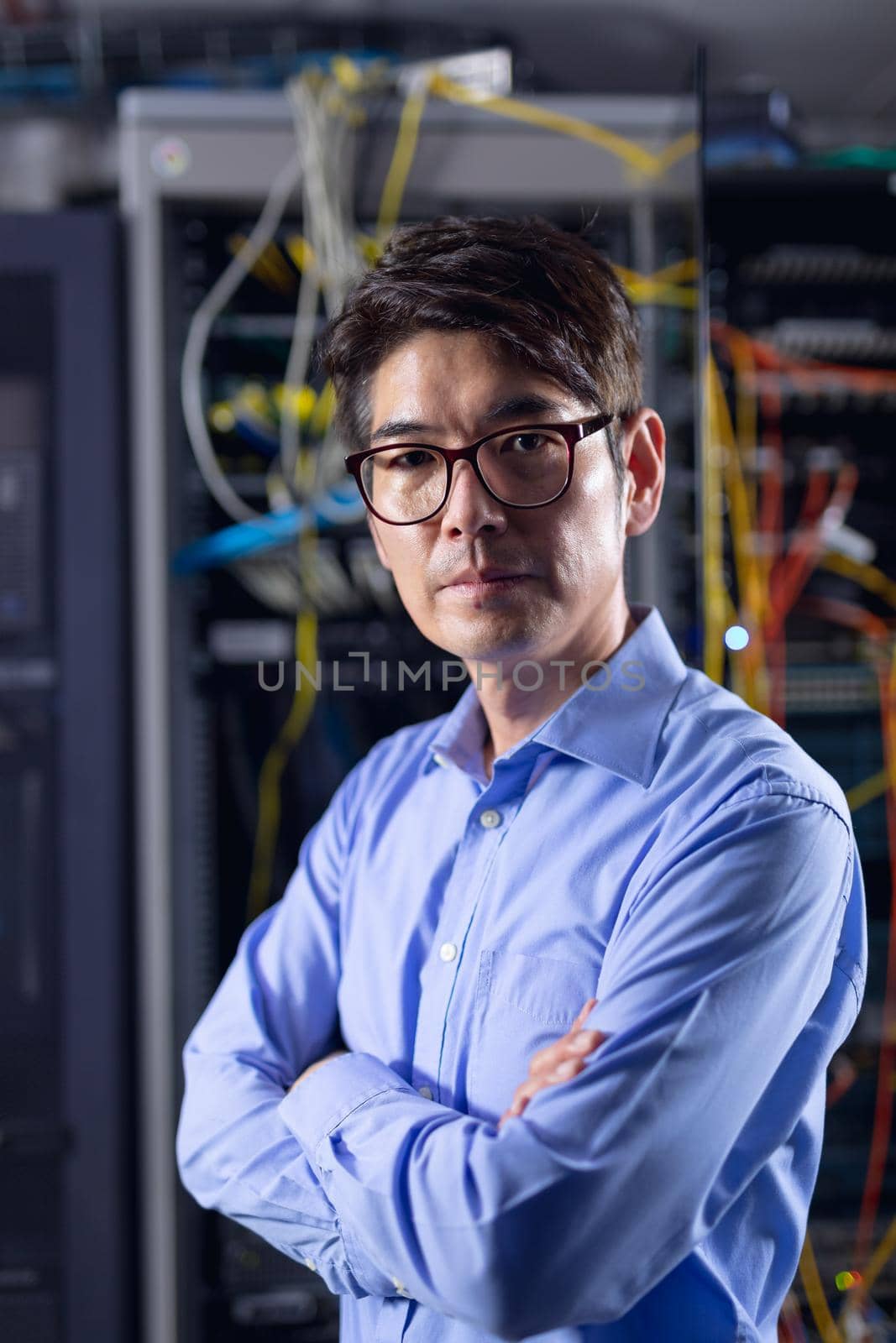 Portrait of asian male engineer with arms crossed in computer server room. database server management and maintenance concept