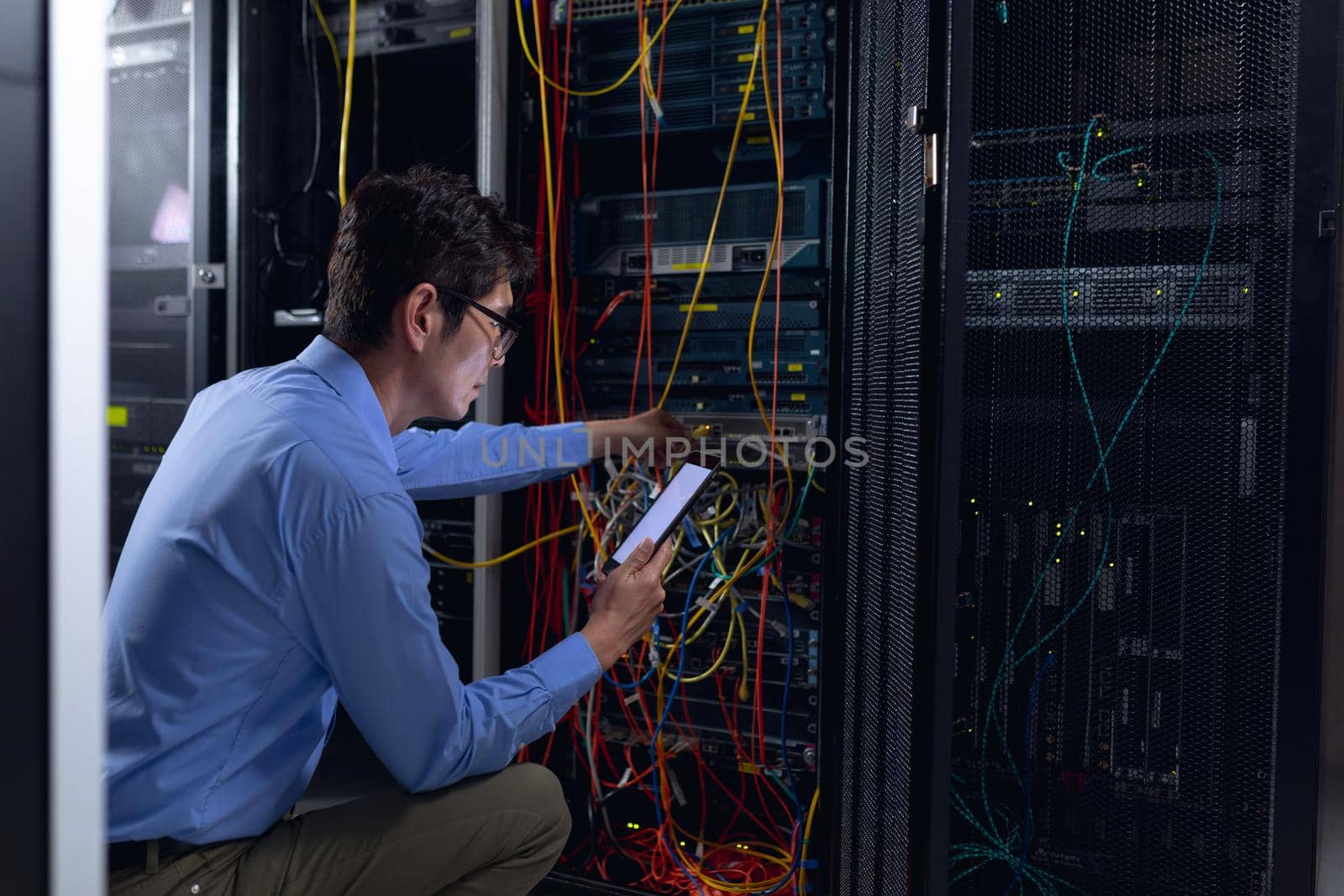 Asian male engineer using digital tablet and inspecting computer server in computer server room by Wavebreakmedia