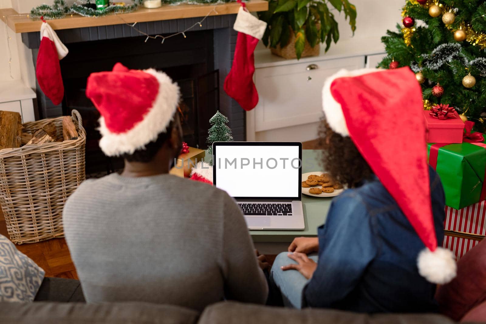 Back view of african american couple wearing santa hats, using laptop with copy space on screen by Wavebreakmedia