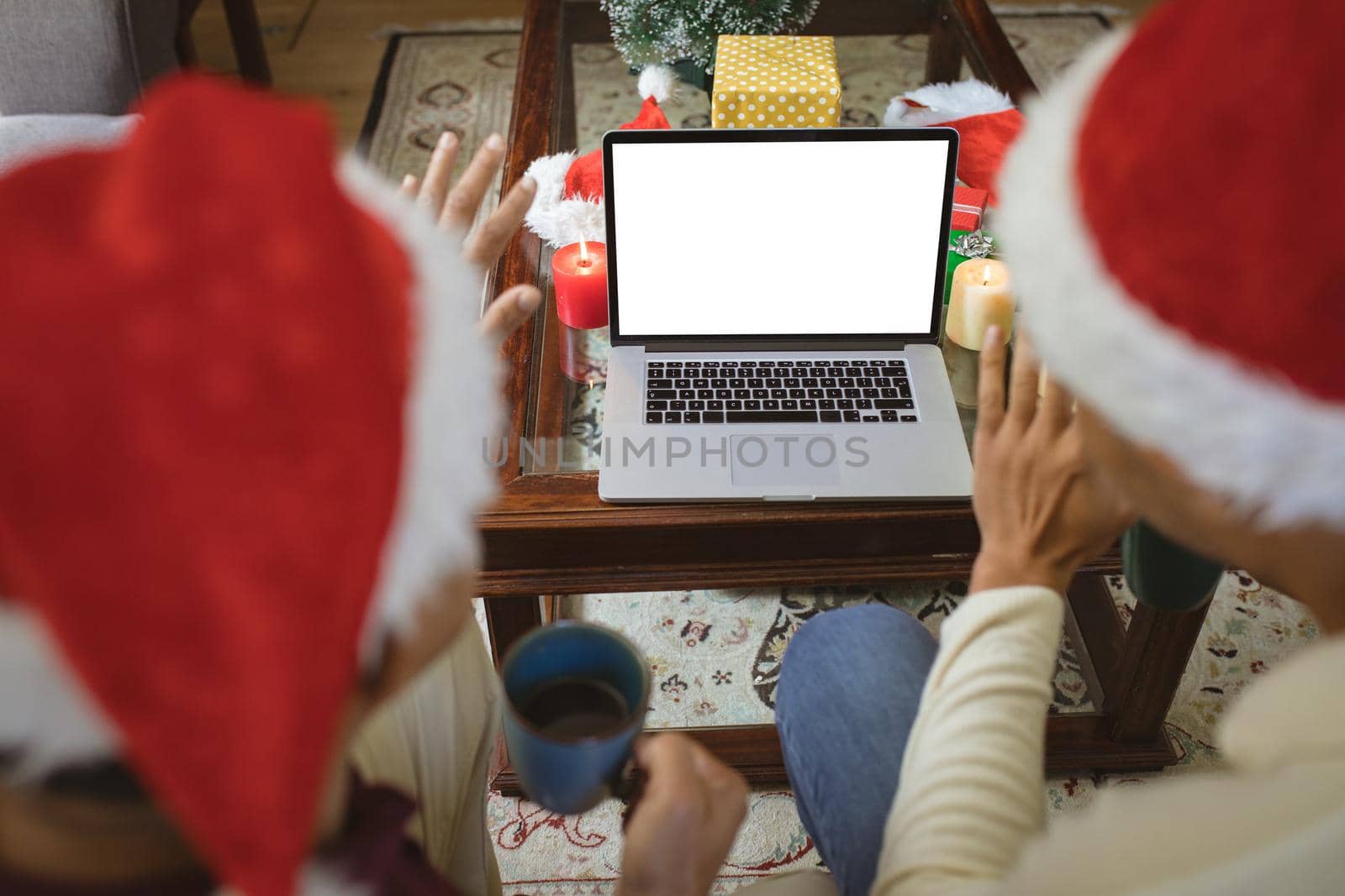 Biracial adult son and senior father in santa hats making laptop christmas video call. christmas, festivity and communication technology.
