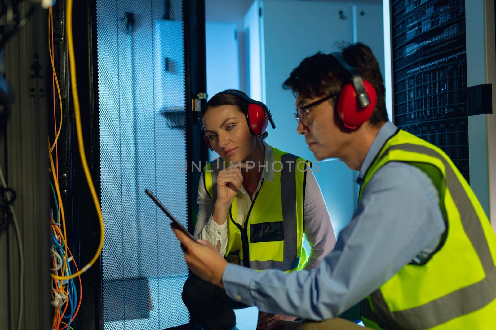 Diverse male and female engineer using digital tablet while inspecting in computer server room by Wavebreakmedia