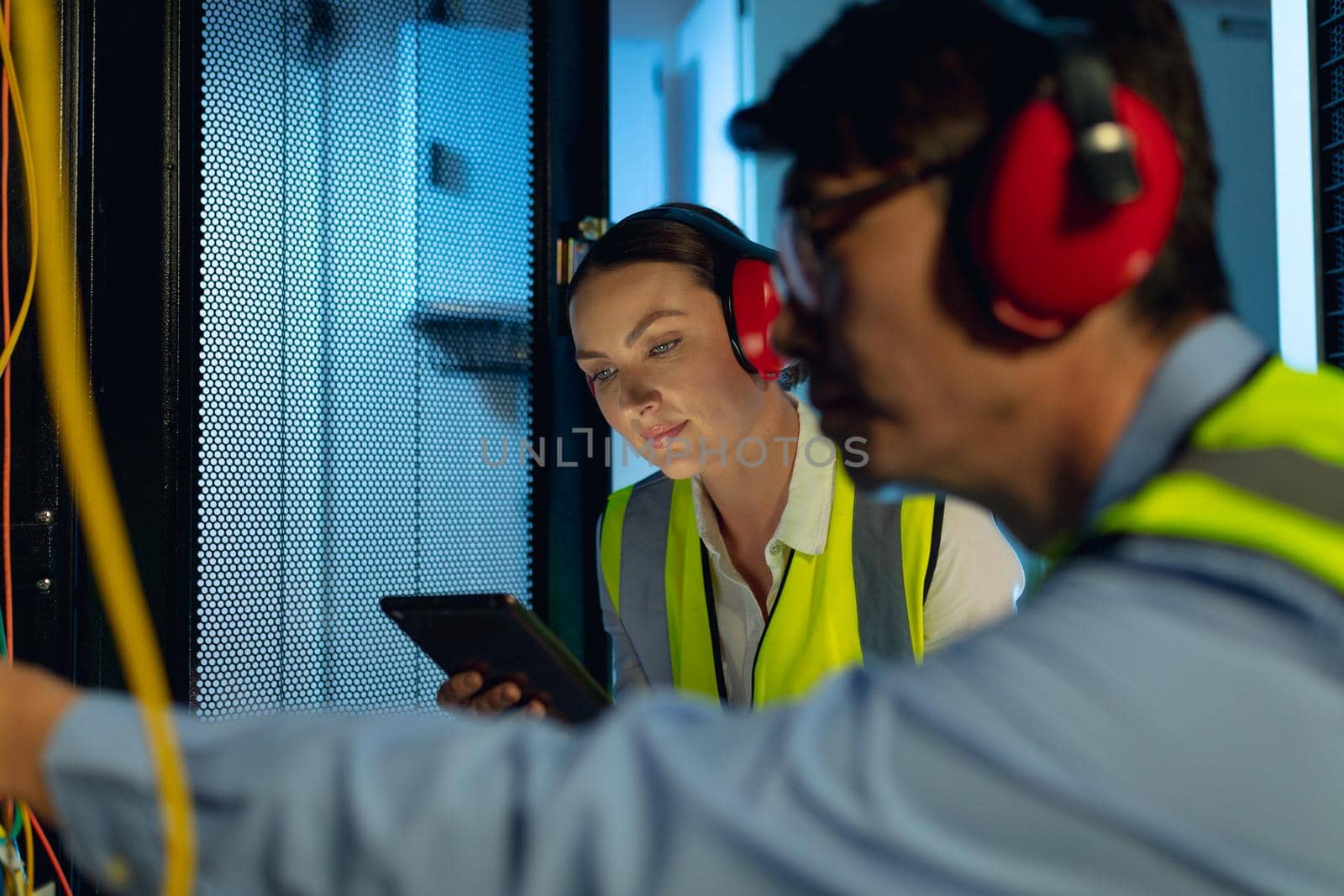 Diverse male and female engineer using digital tablet while inspecting in computer server room. database server management and maintenance concept
