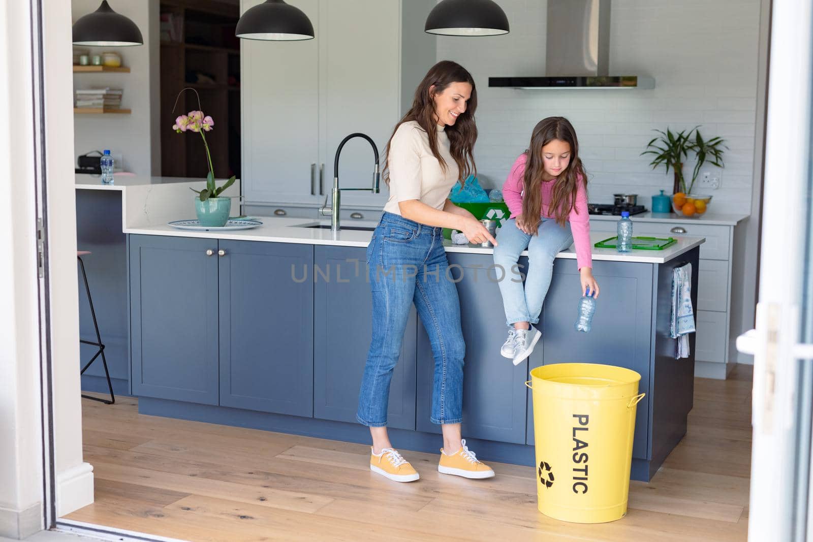 Happy caucasian mother and daughter segregating rubbish. recycling, waste selection, spending time together at home.