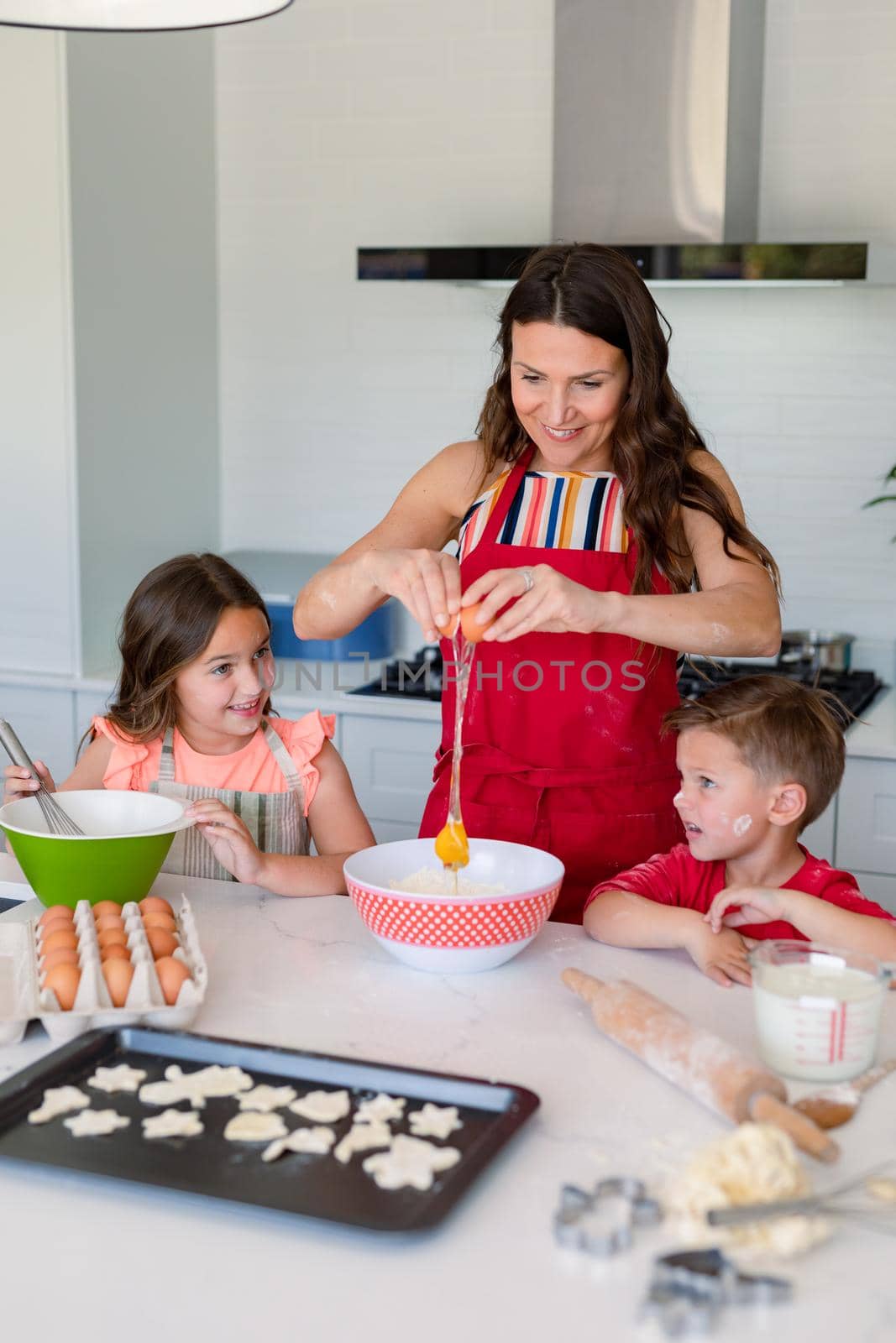 Happy caucasian mother, daughter and son baking together, making cookies in kitchen. family time, having fun together at home.