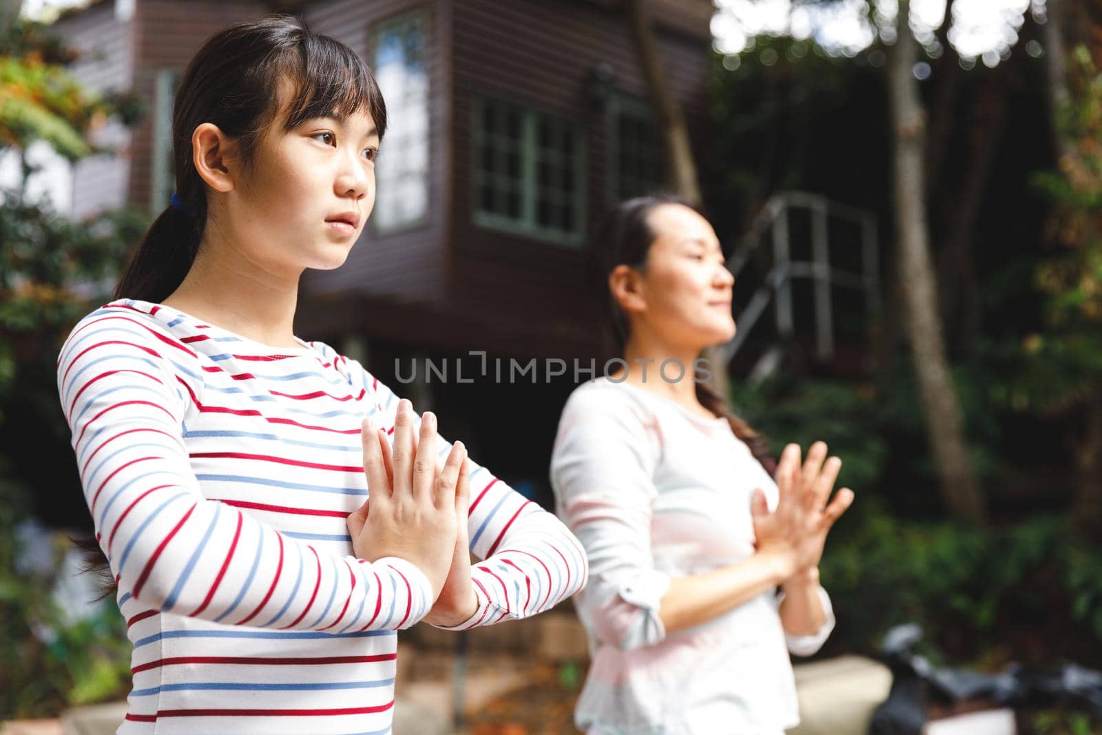 Asian mother and daughter exercising outdoors and practicing tai chi by Wavebreakmedia