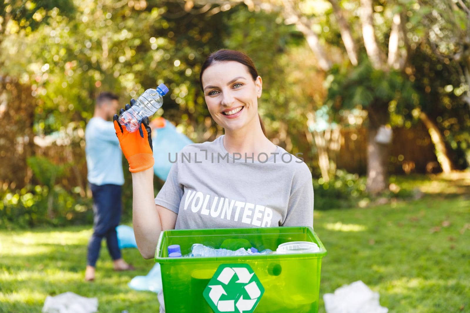 Portrait of smiling caucasian woman holding recycling box, cleaning up countryside with husband. eco conservation volunteers, countryside clean-up.