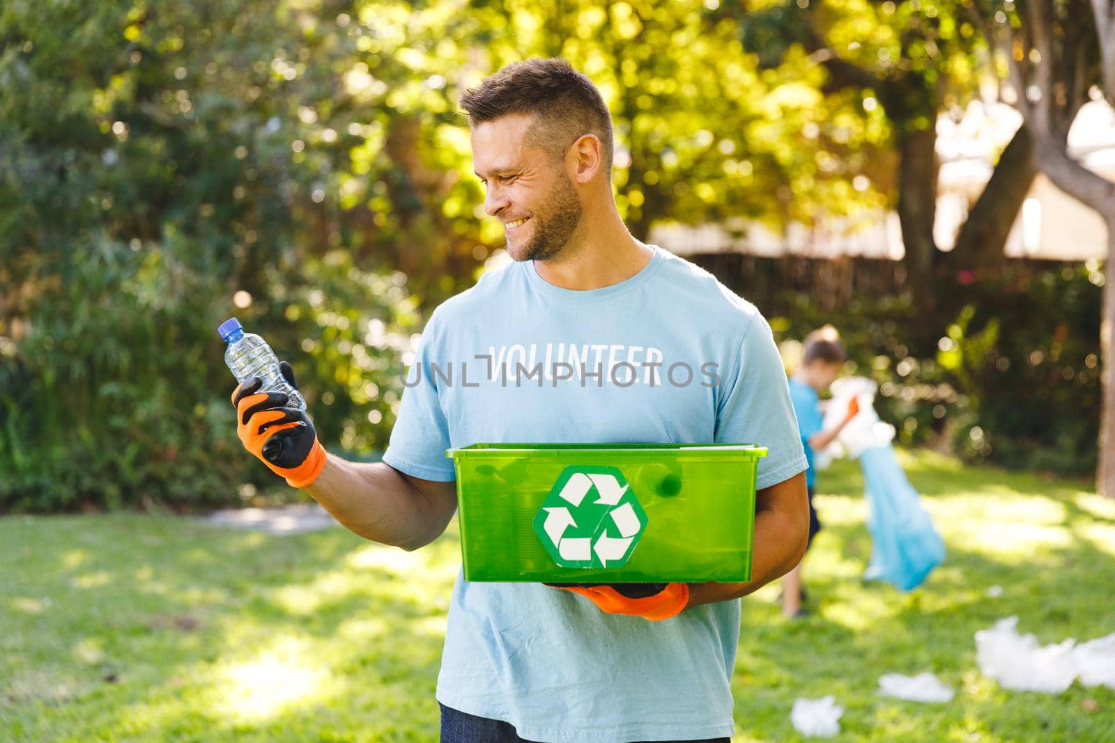 Smiling caucasian man holding recycling box, cleaning up countryside with camily. eco conservation volunteers, countryside clean-up.