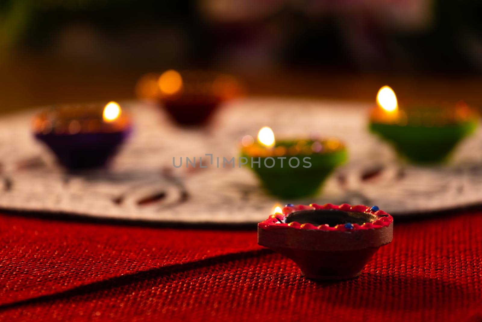 Four lit candles in small decorative clay pots burning on wooden table top. celebration, religion, tradition and ceremony concept.