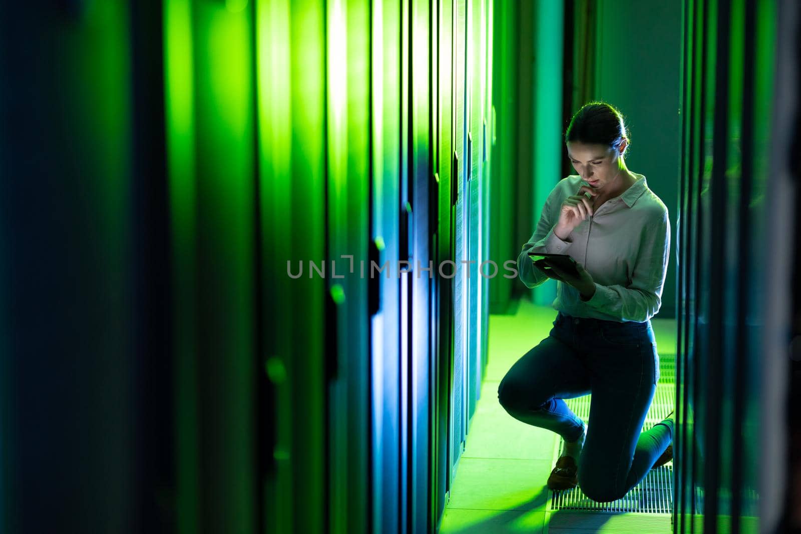 Caucasian female engineer using digital tablet while inspecting in computer server room. database server management and maintenance concept