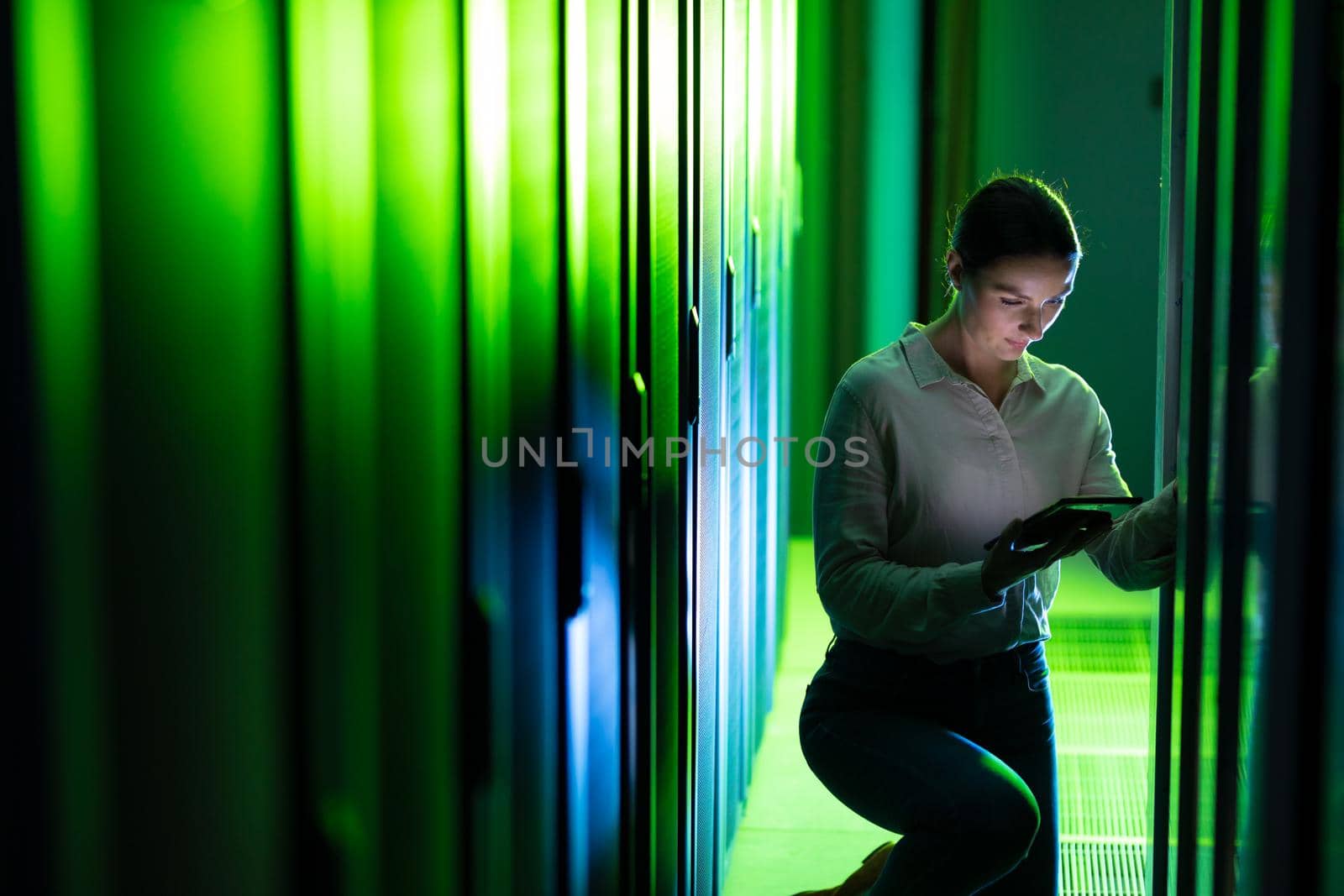 Caucasian female engineer using digital tablet while inspecting in computer server room. database server management and maintenance concept